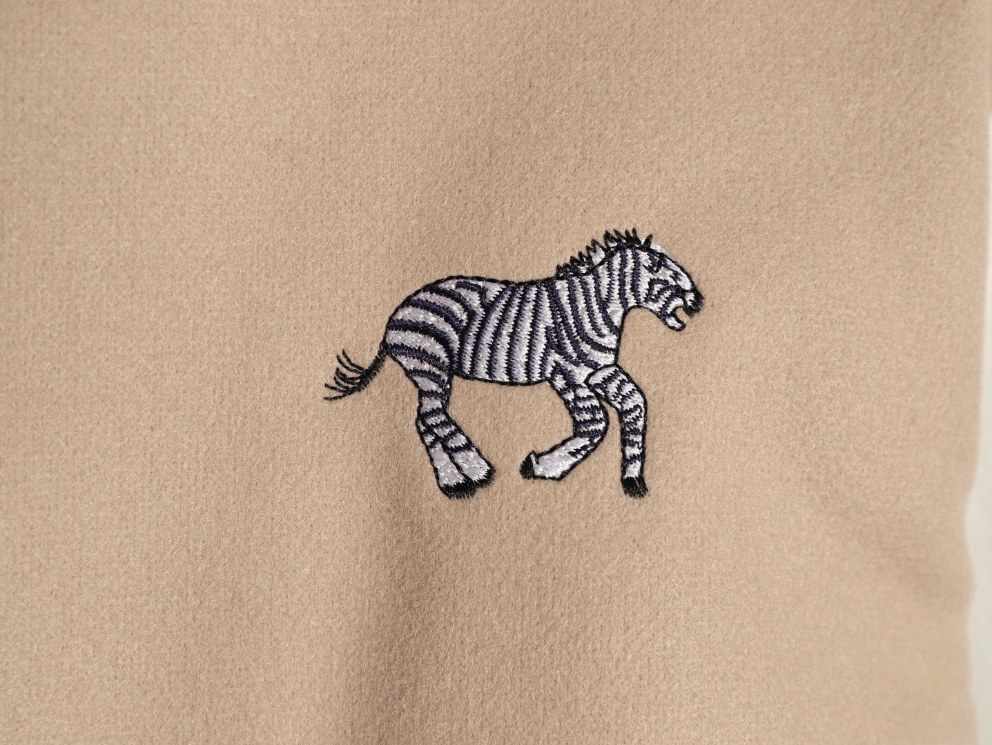 Louis Vuitton/路易威登 26ss 動物樂園刺繡棒球服外套
材質拼接：衣身採用淺卡其色羊毛混紡面料，柔軟且有挺括感；袖子為奶白色荔枝紋牛皮，質感細膩，淺色系搭配更顯清爽。

• 裝飾亮點：衣身滿印精緻動物刺繡（長頸鹿、斑馬、大象、黑豹等）與棕櫚樹圖案，左胸綴有“L.V.M.”字母標識，充滿童趣與度假感，辨識度極高。

• 版型結構：經典棒球服版型，羅紋條紋領口/袖口/下擺，防風收型；正面按扣開合，兩側配白色撞色插袋，兼顧實用性與設計感。
N SIZE:S-XL
