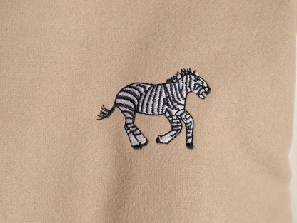 Louis Vuitton/路易威登 26ss 動物樂園刺繡棒球服外套
材質拼接：衣身採用淺卡其色羊毛混紡面料，柔軟且有挺括感；袖子為奶白色荔枝紋牛皮，質感細膩，淺色系搭配更顯清爽。

• 裝飾亮點：衣身滿印精緻動物刺繡（長頸鹿、斑馬、大象、黑豹等）與棕櫚樹圖案，左胸綴有“L.V.M.”字母標識，充滿童趣與度假感，辨識度極高。

• 版型結構：經典棒球服版型，羅紋條紋領口/袖口/下擺，防風收型；正面按扣開合，兩側配白色撞色插袋，兼顧實用性與設計感。
N SIZE:S-XL
