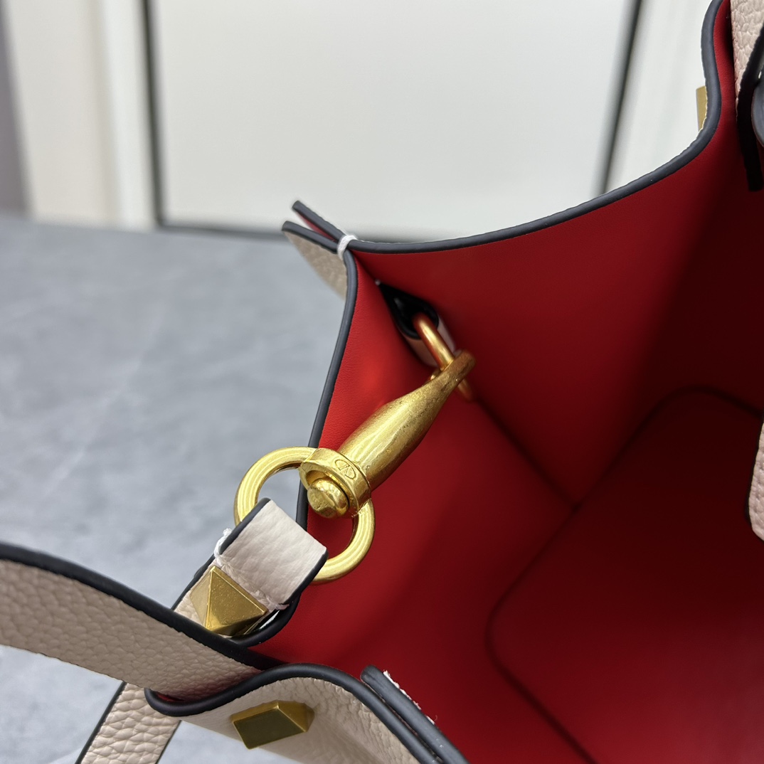 荔枝紋 Garavani VLOGO Escape 小牛皮小號購物袋，包袋兩側點綴紅色細節，金屬徽標飾件可用在包裝內部作為開合，亦可用在外部作為裝飾元素。
小號尺寸：31 *25*15 cm