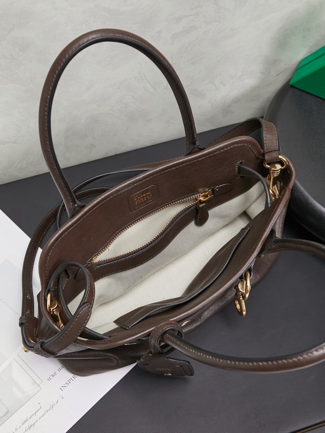 Aventure包袋展现出简约随性的魅力。重新诠释经典线条，这款柔软的Nappa变体展现出多功能和实用的态度，并通过精致独特的细节得到提升。aventure nappa皮革手袋灵感源自miu典藏设计，结构经过调整，变得更加轻便，焕发全新个性，饰以压花字母徽标，增添标志性元素，复古金色五金配件，亚麻混纺衬里，配拉链口袋和贴袋，长手腕适合用作手提或单肩