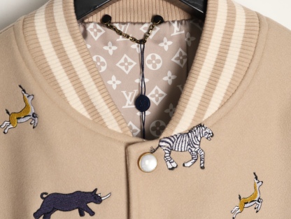 Louis Vuitton/路易威登 26ss 動物樂園刺繡棒球服外套
材質拼接：衣身採用淺卡其色羊毛混紡面料，柔軟且有挺括感；袖子為奶白色荔枝紋牛皮，質感細膩，淺色系搭配更顯清爽。

• 裝飾亮點：衣身滿印精緻動物刺繡（長頸鹿、斑馬、大象、黑豹等）與棕櫚樹圖案，左胸綴有“L.V.M.”字母標識，充滿童趣與度假感，辨識度極高。

• 版型結構：經典棒球服版型，羅紋條紋領口/袖口/下擺，防風收型；正面按扣開合，兩側配白色撞色插袋，兼顧實用性與設計感。
N SIZE:S-XL
