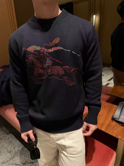 🔝BURBERRY巴寶莉BBR 彩色大戰馬馬術徽標羊毛混紡毛衣
甄選羊毛為主體，羊絨為輔的黃金配比混紡面料，以厚實紗線織就，觸感如雲朵般柔軟豐盈。羊毛的挺括與羊絨的細膩交織，既保留了天然纖維的透氣保暖特性，又賦予織物恰到好處的垂墜感，上身輕盈無負擔。細膩的針織紋理在光線下呈現柔和光澤，深色基調更凸顯面料的高級質感，為秋冬穿搭注入溫暖底蘊。
羅紋針織裝飾：領口、袖口及下擺採用羊毛和羊絨加少量彈性纖維和聚酰胺的羅紋織法，緊密而富有彈性的線圈結構，確保穿著時貼合身形不易變形，兼具舒適包裹感與利落廓