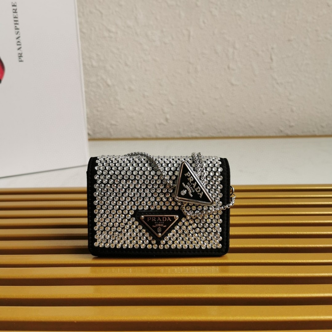 【 原單】🎉項鍊水晶小包🎉1MR024新色🎉🎉這款Duchesse面料卡片夾通體飾以仿水晶，於表面營造出光影格調和虹彩炫色，彰顯華美且不失功能性的設計。最愛是這條可拆卸可調節鐵璉肩帶，又可當腰包裝飾😍😍又可當搭配衣服項鍊裝飾，中間三角形標可調節活動，賦予單品多樣的佩戴方式。空間可裝口紅💄/耳機/鑰匙🚗....夜燈下bling bling,太美了。值得入手🎉🎉尺寸：長11.5cm*高8cm