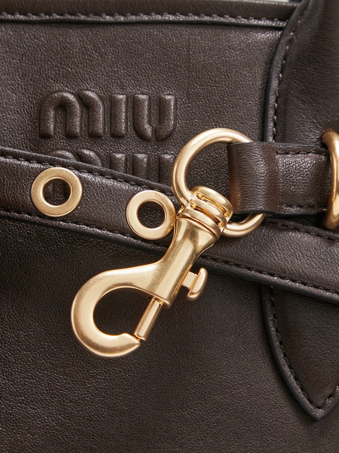 Aventure包袋展现出简约随性的魅力。重新诠释经典线条，这款柔软的Nappa变体展现出多功能和实用的态度，并通过精致独特的细节得到提升。aventure nappa皮革手袋灵感源自miu典藏设计，结构经过调整，变得更加轻便，焕发全新个性，饰以压花字母徽标，增添标志性元素，复古金色五金配件，亚麻混纺衬里，配拉链口袋和贴袋，长手腕适合用作手提或单肩