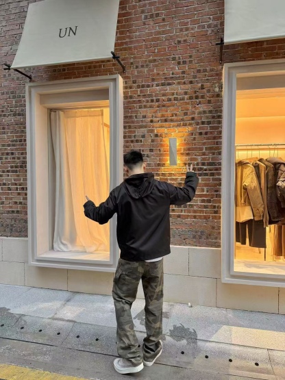 🔝PRADA/普拉達PRD 拉鍊口袋尼龍連帽外套
選用品牌標誌性的再生尼龍面料，與傳統尼龍性能相當，具備高強度，抗撕裂，耐磨損等特性。其質地輕盈，同時又具備防水功能適合多場景需求。抗皺，快乾的特點也易於日常打理維護。
定制三角徽標通過4個0.8mm金屬爪釘固定於衣身，爪釘背面經手工打磨至圓潤，避免刮蹭。下擺彈力抽繩選用7芯高彈尼龍繩，直徑3mm，配合橡膠扣，可實現±5cm長度調節。抽繩孔採用「金屬雞眼+防磨環」雙重保護，雞眼內徑5mm，邊緣光滑無毛刺，反復抽拉500次無變形。
袖口採用紐扣調