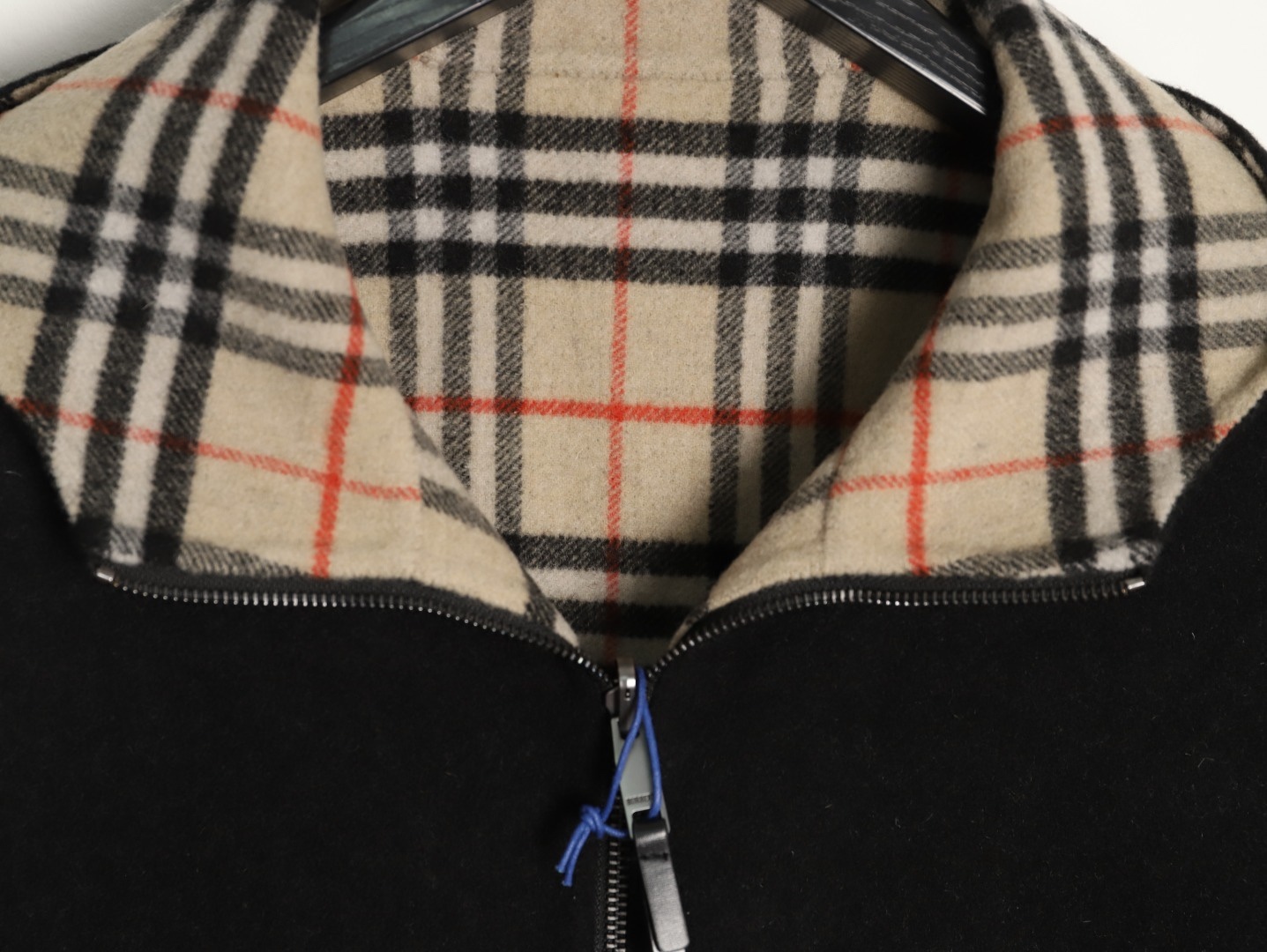 🔝BURBERRY巴寶莉BBR 雙面穿羊毛連帽外套
精選雙面羊毛斜紋面料，通過獨特的拉絨工藝處理，使表層呈現細膩豐盈的絨毛質感，觸感如雲朵般柔軟親膚，同時保留羊毛天然的保暖性與透氣性。一面以沈穩黑色演繹低調奢華，另一面則鋪滿標誌性的紅、黑、駝三色交織的經典圖案，既是品牌視覺符號，也為穿搭注入復古氣息。雙面可穿的設計，讓一件外套擁有兩種風格。
選用優質羊絨纖維進行精細紡紗，確保紗線的均勻性和強度。然後，通過先進的織造技術將紗線織成具有雙面效果的毛呢面料。
面料在裁剪前會經過預縮處理