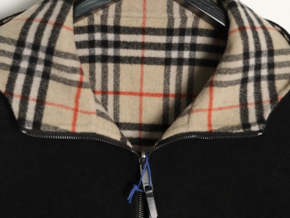 🔝BURBERRY巴寶莉BBR 雙面穿羊毛連帽外套
精選雙面羊毛斜紋面料，通過獨特的拉絨工藝處理，使表層呈現細膩豐盈的絨毛質感，觸感如雲朵般柔軟親膚，同時保留羊毛天然的保暖性與透氣性。一面以沈穩黑色演繹低調奢華，另一面則鋪滿標誌性的紅、黑、駝三色交織的經典圖案，既是品牌視覺符號，也為穿搭注入復古氣息。雙面可穿的設計，讓一件外套擁有兩種風格。
選用優質羊絨纖維進行精細紡紗，確保紗線的均勻性和強度。然後，通過先進的織造技術將紗線織成具有雙面效果的毛呢面料。
面料在裁剪前會經過預縮處理