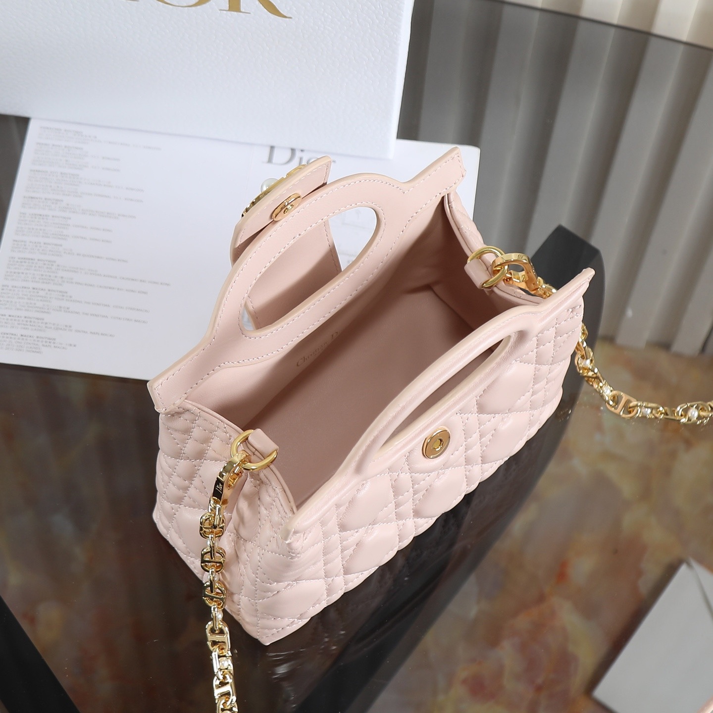 原廠級 粉色鏈條手袋
這款 Dior Jolie Top Handle 迷你鏈條手袋是二零二六早春成衣系列新品，呈現出優雅精緻的設計。採用黑色羊皮革精心製作，飾以藤格紋，翻蓋點綴以金色飾面金屬 CD 標誌和白色樹脂珠飾。內設一個隔層，可收納各種日常用品。搭配雙頂部手柄和可調節、可拆卸 CD 鏈條肩帶，肩帶由皮革帶和 CD 鏈環組成，飾以白色樹脂珠飾，可舒適手提、肩背或斜挎，可與日常或晚裝造型搭配。
