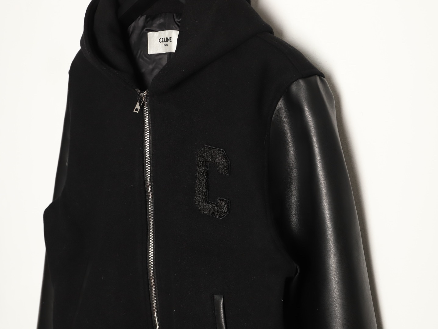🔝CELINE賽琳CE 大C毛呢皮袖連帽外套
主體採用羊毛混紡面料，經特殊編織工藝打造，質地厚實而不失柔軟，呈現細膩的啞光光澤。羊毛纖維經過預縮處理，有效避免穿著後的變形與起球，同時保留天然的保暖性與透氣性。衣袖部分選用皮革，通過特殊處理賦予皮革細膩的粒面紋理與溫潤光澤，隨著穿著會逐漸形成獨特的使用痕跡，成為專屬的時光印記。內襯採用100%粘膠纖維，手感絲滑且垂墜感佳，與面料形成良好的內外呼應，提升穿著舒適度。
胸前C字貼飾採用毛巾繡工藝，以6mm粗細的紗線層層堆疊，形成飽滿的立體肌理。刺繡
