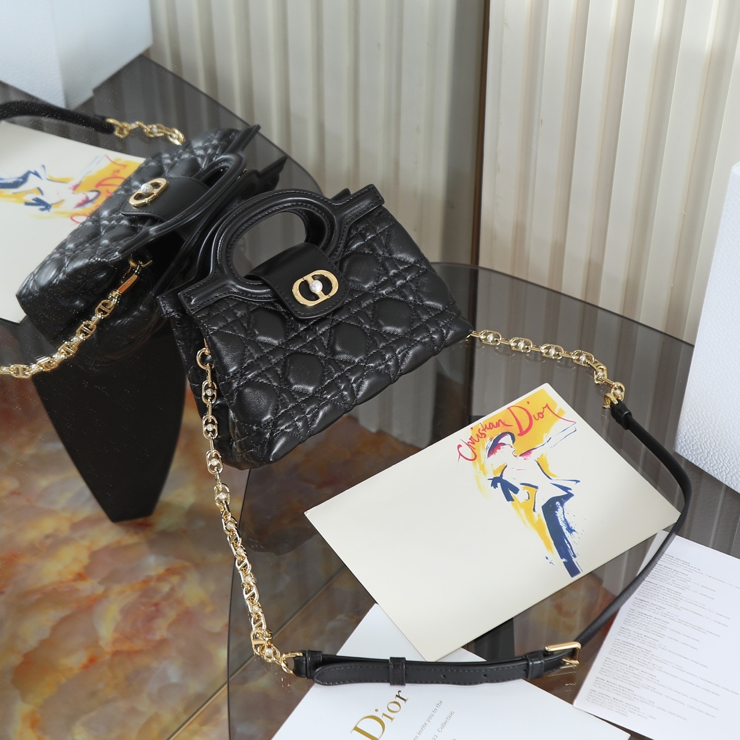 原廠級 黑色鏈條手袋
這款 Dior Jolie Top Handle 迷你鏈條手袋是二零二六早春成衣系列新品，呈現出優雅精緻的設計。採用黑色羊皮革精心製作，飾以藤格紋，翻蓋點綴以金色飾面金屬 CD 標誌和白色樹脂珠飾。內設一個隔層，可收納各種日常用品。搭配雙頂部手柄和可調節、可拆卸 CD 鏈條肩帶，肩帶由皮革帶和 CD 鏈環組成，飾以白色樹脂珠飾，可舒適手提、肩背或斜挎，可與日常或晚裝造型搭配。
