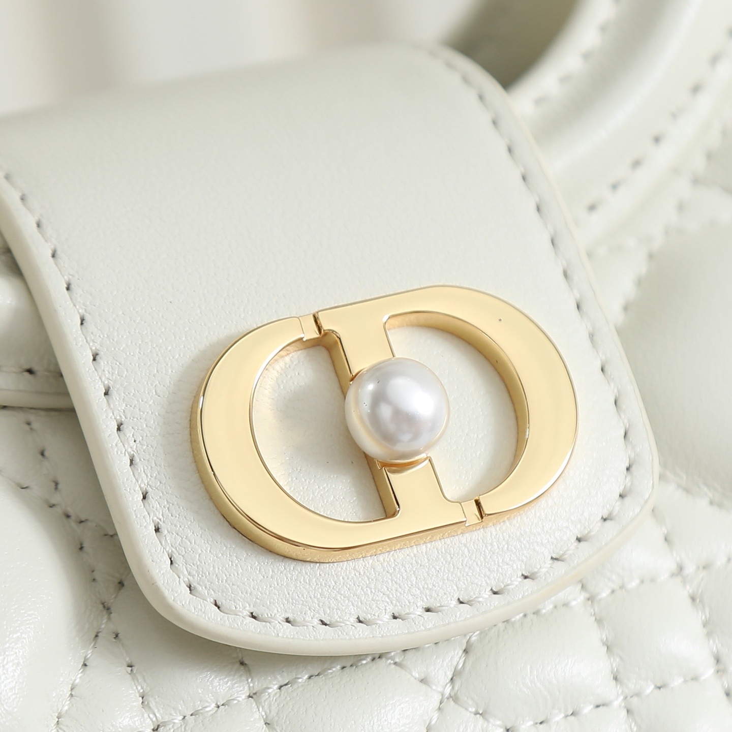 原廠級 白色鏈條手袋
這款 Dior Jolie Top Handle 迷你鏈條手袋是二零二六早春成衣系列新品，呈現出優雅精緻的設計。採用黑色羊皮革精心製作，飾以藤格紋，翻蓋點綴以金色飾面金屬 CD 標誌和白色樹脂珠飾。內設一個隔層，可收納各種日常用品。搭配雙頂部手柄和可調節、可拆卸 CD 鏈條肩帶，肩帶由皮革帶和 CD 鏈環組成，飾以白色樹脂珠飾，可舒適手提、肩背或斜挎，可與日常或晚裝造型搭配。
