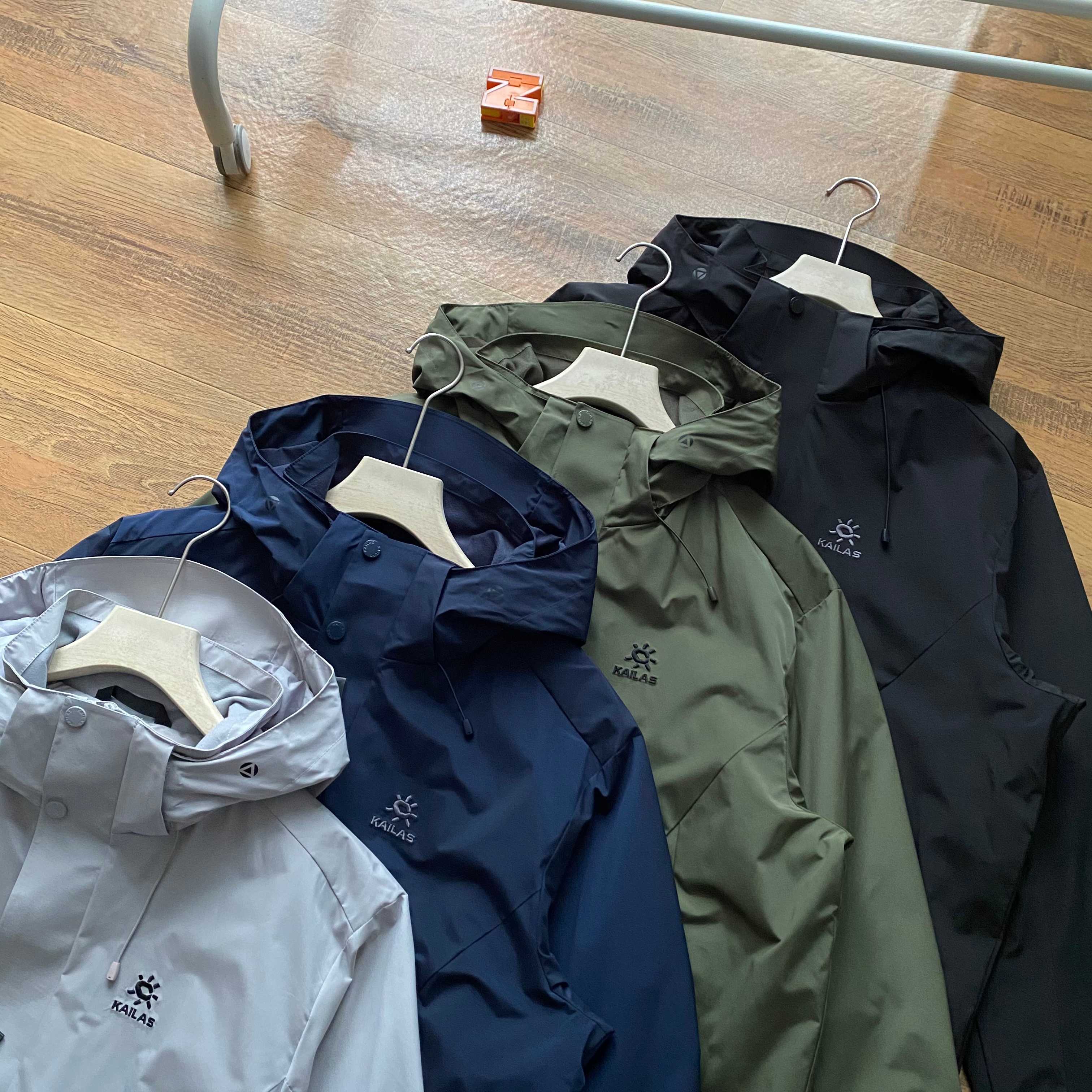 新款連帽三色風衣凱樂石KALIAS春季男子速乾輕薄外套 它的連帽設計，不僅時尚，還能在多變天氣中為你遮風擋雨。精選優質面料，觸感舒適，穿著自在無束縛，且具備良好的透氣性與耐磨性，滿足你的各種活動需求。版型上，注重亞洲人體型特點，舒適百搭，可輕鬆搭配各類下裝。無論是搭配牛仔褲展現休閒風，還是搭配工裝褲凸顯硬朗氣質，都毫無壓力。細節之處盡顯品質，精緻的縫線工藝，耐用的拉鍊與扣件，每一處都經過精心考量，只為給你帶來極致的穿著體驗。真正的3D立體裁剪，袖口添加魔術貼可自由調節 真正做到貼合身材比例，