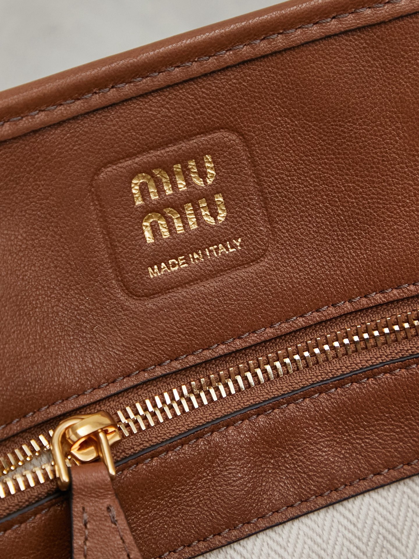 Aventure包袋展现出简约随性的魅力。重新诠释经典线条，这款柔软的Nappa变体展现出多功能和实用的态度，并通过精致独特的细节得到提升。aventure nappa皮革手袋灵感源自miu典藏设计，结构经过调整，变得更加轻便，焕发全新个性，饰以压花字母徽标，增添标志性元素，复古金色五金配件，亚麻混纺衬里，配拉链口袋和贴袋，长手腕适合用作手提或单肩
