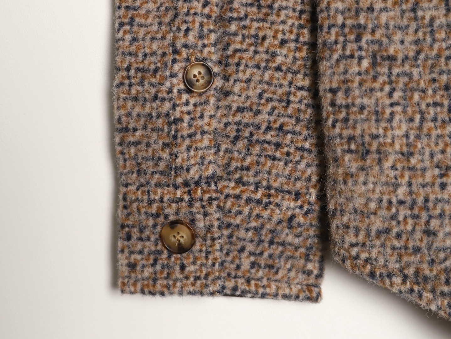 🔝LOEWE羅意威 皮章口袋羊毛混紡外套
採用精心配比的混紡面料，羊毛提供天然保暖與挺括廓形，馬海毛賦予面料細膩蓬松的絨毛感，少量錦綸的餵入則增強耐磨性與抗皺性，三者融合打造中克重的理想厚度，兼顧溫度與輕盈。通過“雙面磨毛”工藝處理，面料表面呈現豐盈的短絨毛肌理，觸感如羊絨般柔軟親膚，同時保留羊毛混紡的筋骨感。微型格紋圖案以沙米色為基底，交織灰、棕、藍三色紗線，通過色織工藝織就，微型格紋尺寸統一，細膩而不張揚，呈現低調的復古韻味。
面料經過3道磨毛工序，確保絨毛長度均勻（约0.3mm）