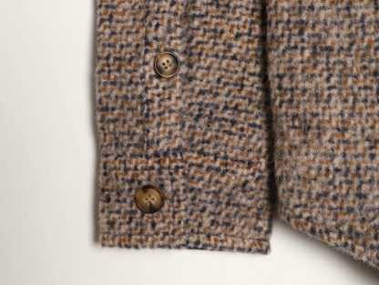 🔝LOEWE羅意威 皮章口袋羊毛混紡外套
採用精心配比的混紡面料，羊毛提供天然保暖與挺括廓形，馬海毛賦予面料細膩蓬松的絨毛感，少量錦綸的餵入則增強耐磨性與抗皺性，三者融合打造中克重的理想厚度，兼顧溫度與輕盈。通過“雙面磨毛”工藝處理，面料表面呈現豐盈的短絨毛肌理，觸感如羊絨般柔軟親膚，同時保留羊毛混紡的筋骨感。微型格紋圖案以沙米色為基底，交織灰、棕、藍三色紗線，通過色織工藝織就，微型格紋尺寸統一，細膩而不張揚，呈現低調的復古韻味。
面料經過3道磨毛工序，確保絨毛長度均勻（约0.3mm）