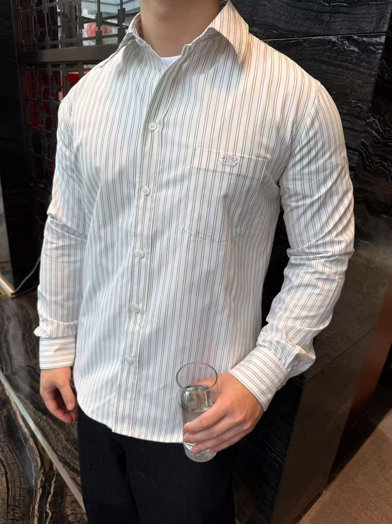 🔝CELINE賽琳CE 凱旋門竪條紋刺繡長袖襯衫
採用100%天然棉花纖維，無任何化纖混紡，從源頭確保面料的純淨度。棉纖維內部的中空結構形成天然“空氣通道”，使面料具備優異的透氣性。空氣可自由流通於纖維間隙，快速排出體表濕氣與熱量，即使長時間穿著也能保持乾爽，避免悶熱黏膩感。同時吸濕性遠超合成纖維。當人體出汗時，面料能迅速吸收汗液並擴散至表面，通過空氣流動加速蒸發，實現“吸濕-釋放”的動態平衡，保持肌膚乾爽舒適。
繡花機以棉線勾勒標誌，針腳細密均勻，確保線條流暢清晰，形成飽滿的立體肌理。刺繡