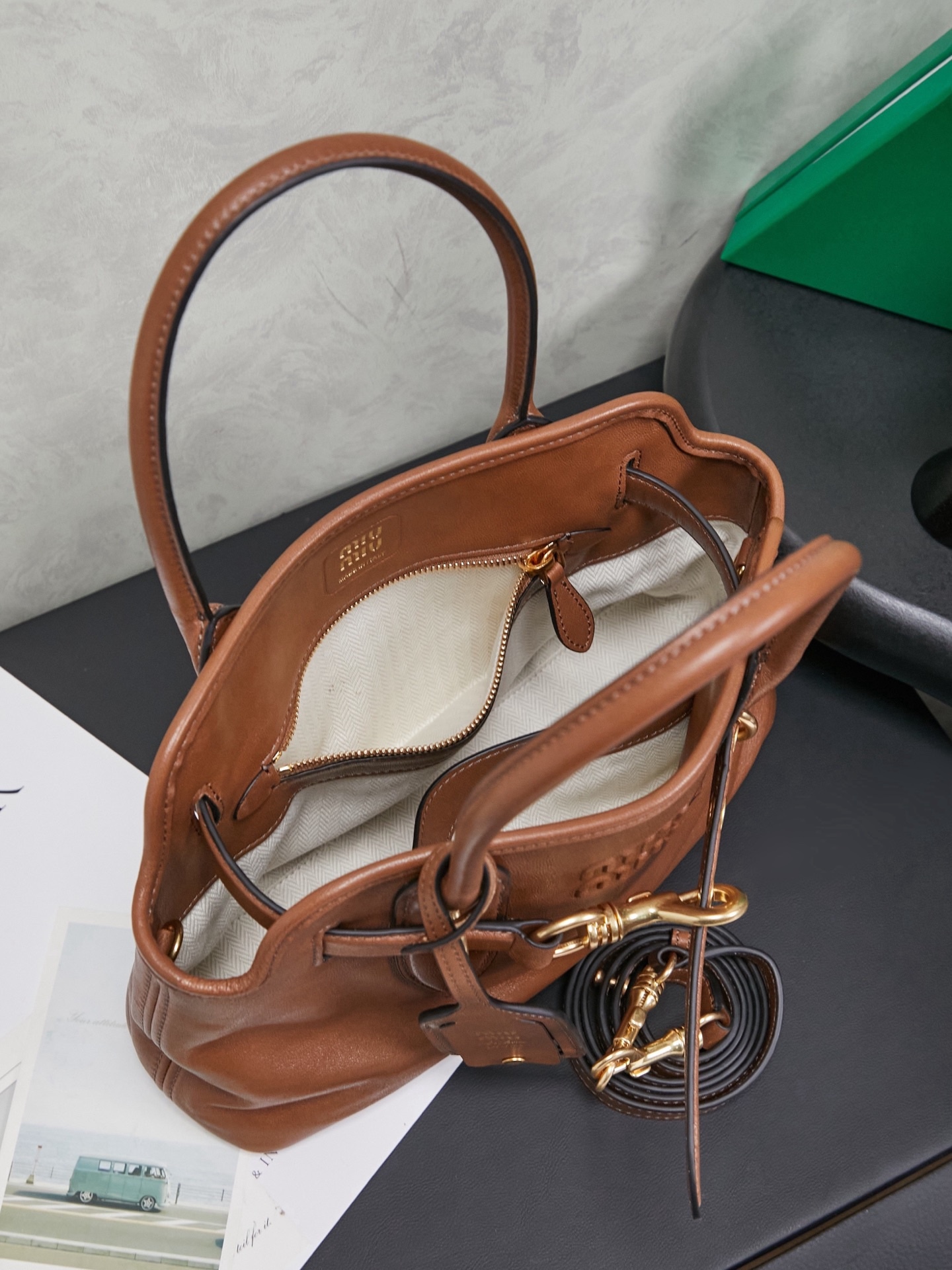 Aventure包袋展现出简约随性的魅力。重新诠释经典线条，这款柔软的Nappa变体展现出多功能和实用的态度，并通过精致独特的细节得到提升。aventure nappa皮革手袋灵感源自miu典藏设计，结构经过调整，变得更加轻便，焕发全新个性，饰以压花字母徽标，增添标志性元素，复古金色五金配件，亚麻混纺衬里，配拉链口袋和贴袋，长手腕适合用作手提或单肩
