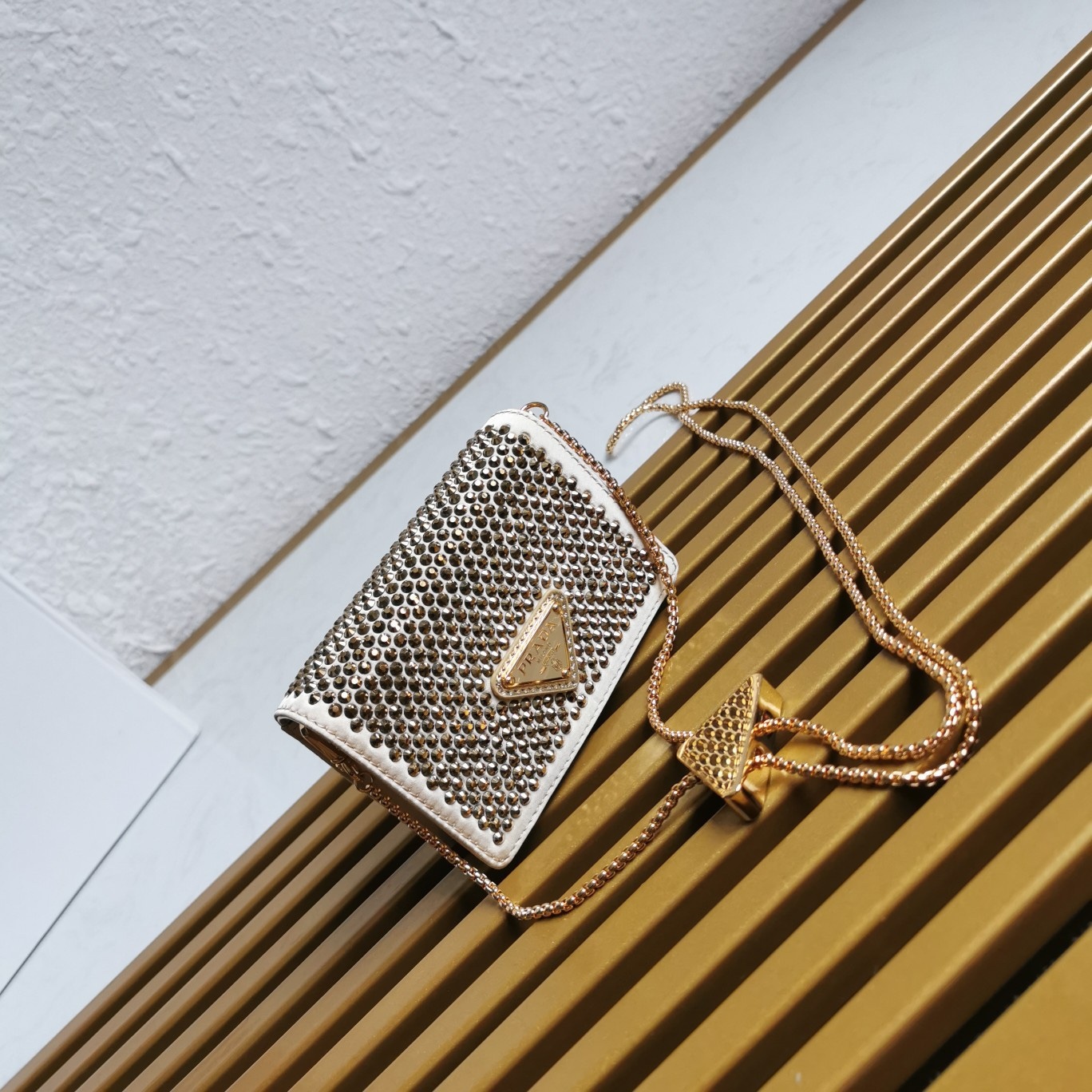 【 原單】🎉2023新款金色系項鍊水晶小包🎉1MR024🎉🎉這款Duchesse面料卡片夾通體飾以仿水晶，於表面營造出光影格調和虹彩炫色，彰顯華美且不失功能性的設計。最愛是這條可拆卸可調節鐵璉肩帶，又可當腰包裝飾😍😍又可當搭配衣服項鍊裝飾，中間三角形標可調節活動，賦予單品多樣的佩戴方式。空間可裝口紅💄/耳機/鑰匙🚗....夜燈下bling bling,太美了。值得入手🎉🎉尺寸：長11.5cm*高8cm