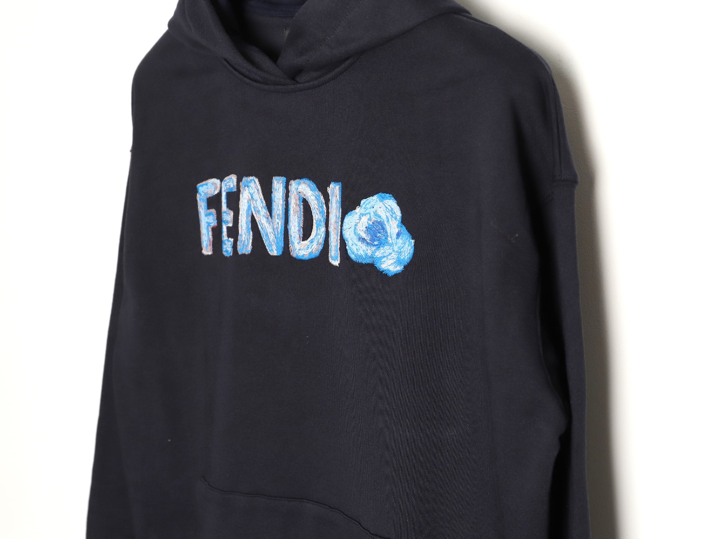 🔝FENDI芬迪FD 藍字母刺繡連帽衛衣
選用100%棉為基底編織而成的單面魚鱗布面料，正面為平滑的針織面，觸膚面通過針織機的浮線編織技術形成立體的毛圈，增加蓬松感， 同時觸感細膩。毛圈結構吸水量大且蒸發快，經過預縮處理之後，縮水率低於2%，確保成衣尺寸穩定。深藍色染整採用活性染料，色澤濃郁飽滿，多次洗滌不易褪色。
胸前“FENDI Flower”圖案採用日本田島繡花機精密刺繡，融合多色漸變與立體肌理，呈現獨特的水彩效果。字母與花朵圖案使用不同深淺的藍白漸變繡線，從淺藍到靛藍自然過渡，