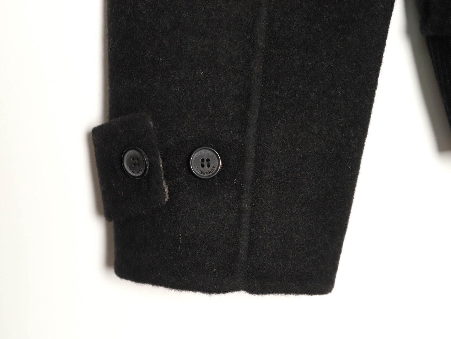 🔝BURBERRY巴寶莉BBR 雙面穿羊毛連帽外套
精選雙面羊毛斜紋面料，通過獨特的拉絨工藝處理，使表層呈現細膩豐盈的絨毛質感，觸感如雲朵般柔軟親膚，同時保留羊毛天然的保暖性與透氣性。一面以沈穩黑色演繹低調奢華，另一面則鋪滿標誌性的紅、黑、駝三色交織的經典圖案，既是品牌視覺符號，也為穿搭注入復古氣息。雙面可穿的設計，讓一件外套擁有兩種風格。
選用優質羊絨纖維進行精細紡紗，確保紗線的均勻性和強度。然後，通過先進的織造技術將紗線織成具有雙面效果的毛呢面料。
面料在裁剪前會經過預縮處理