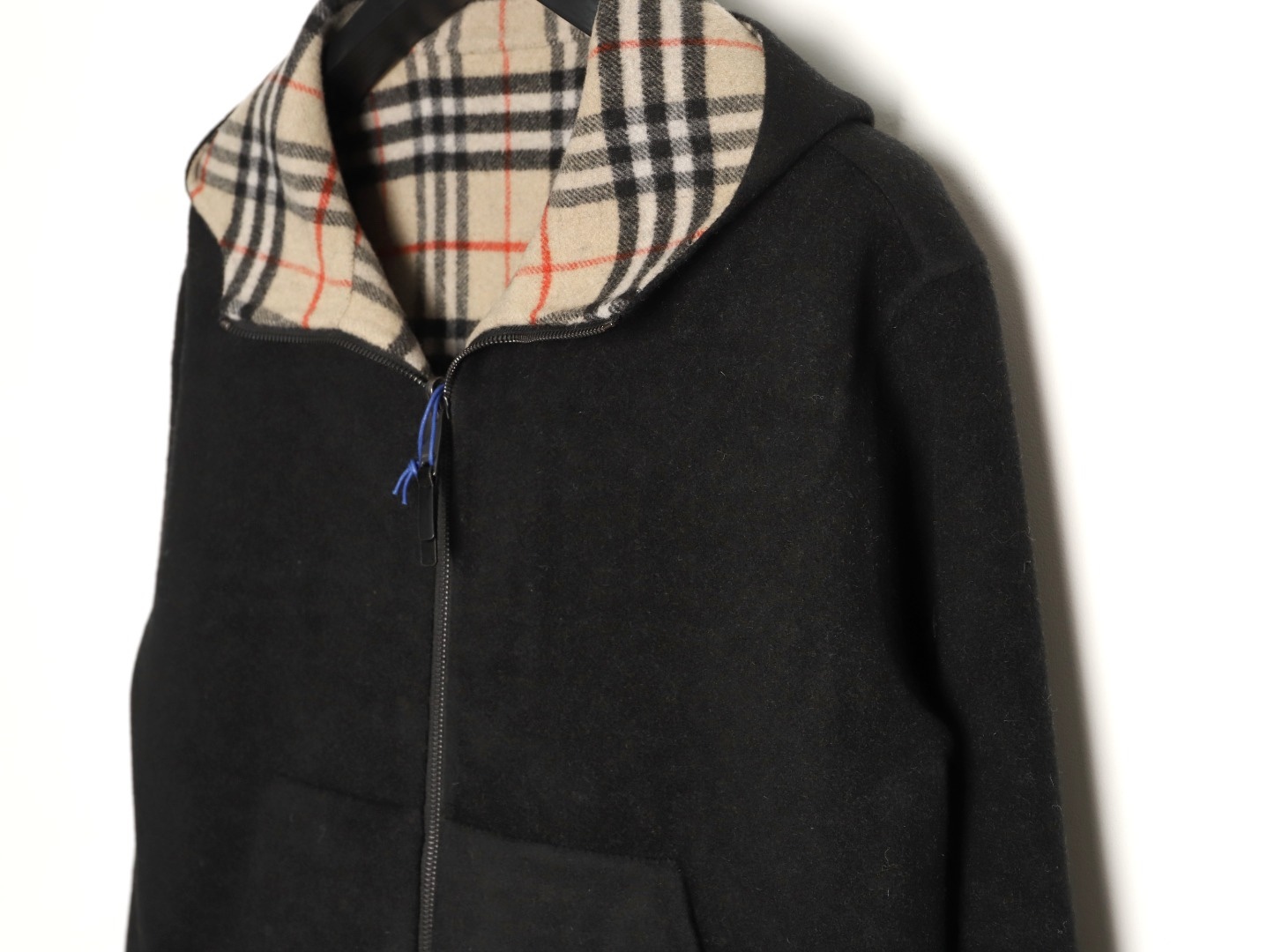 🔝BURBERRY巴寶莉BBR 雙面穿羊毛連帽外套
精選雙面羊毛斜紋面料，通過獨特的拉絨工藝處理，使表層呈現細膩豐盈的絨毛質感，觸感如雲朵般柔軟親膚，同時保留羊毛天然的保暖性與透氣性。一面以沈穩黑色演繹低調奢華，另一面則鋪滿標誌性的紅、黑、駝三色交織的經典圖案，既是品牌視覺符號，也為穿搭注入復古氣息。雙面可穿的設計，讓一件外套擁有兩種風格。
選用優質羊絨纖維進行精細紡紗，確保紗線的均勻性和強度。然後，通過先進的織造技術將紗線織成具有雙面效果的毛呢面料。
面料在裁剪前會經過預縮處理