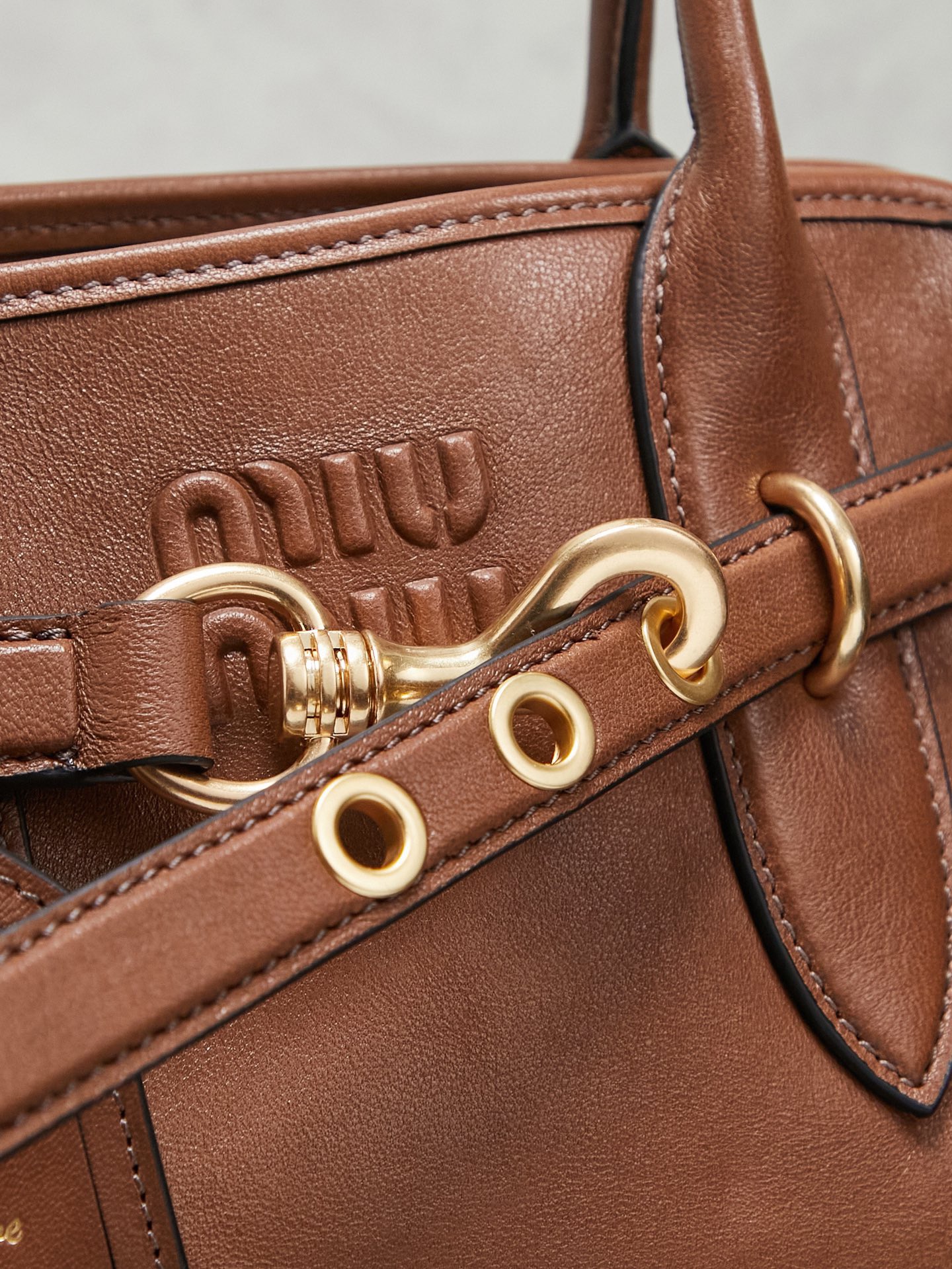 Aventure包袋展现出简约随性的魅力。重新诠释经典线条，这款柔软的Nappa变体展现出多功能和实用的态度，并通过精致独特的细节得到提升。aventure nappa皮革手袋灵感源自miu典藏设计，结构经过调整，变得更加轻便，焕发全新个性，饰以压花字母徽标，增添标志性元素，复古金色五金配件，亚麻混纺衬里，配拉链口袋和贴袋，长手腕适合用作手提或单肩
