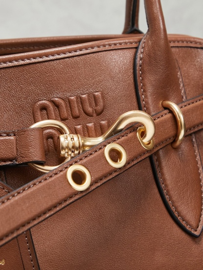 Aventure包袋展现出简约随性的魅力。重新诠释经典线条，这款柔软的Nappa变体展现出多功能和实用的态度，并通过精致独特的细节得到提升。aventure nappa皮革手袋灵感源自miu典藏设计，结构经过调整，变得更加轻便，焕发全新个性，饰以压花字母徽标，增添标志性元素，复古金色五金配件，亚麻混纺衬里，配拉链口袋和贴袋，长手腕适合用作手提或单肩
