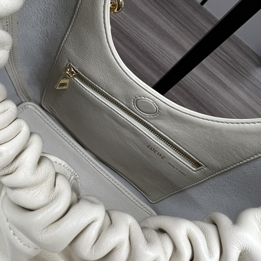 LO℮w℮🌟小號🆕納帕羊皮Squeeze手袋👜一款精緻而柔美的全新手袋，採用觸感柔軟的納帕皮革製成。這款順手藝是傳統工藝、創新研究和獨特設計的傑作，具備令人驚訝的輕盈褶皺包身、可調節甜甜圈鏈條和觸感柔軟的提手。此小號版本採用納帕羊皮革打造。*可肩背、斜挎或手提*可調節鏈條肩帶，搭配Anagram攜刻鵝卵石，附加額外鏈條，可進一步延長肩帶*磁扣開合*內部拉鍊口袋*無襯里*lo*ewe燙金或燙銀。
size：29*10.5*24CM
型號：652329 全鋼五金（配全套包裝）