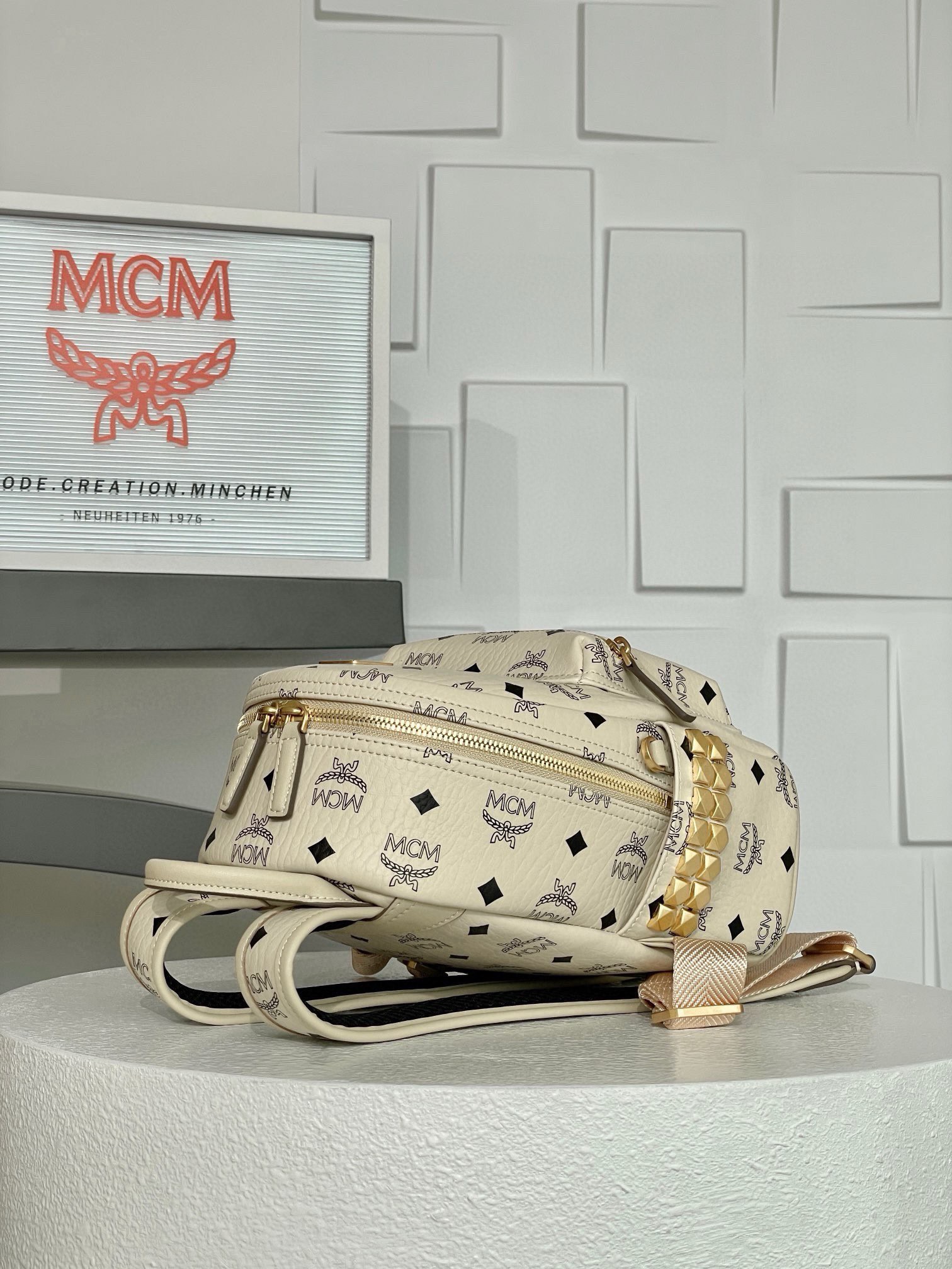 𝗠𝗖𝗠 𝗦𝘁𝗮𝗿𝗸 𝗩𝗶𝘀𝗲𝘁𝗼𝘀🆕新款米白色Mini#铆钉双肩背包·Cp独家®️米白满印
这款新配色双肩背包结构规整，重新定义五金的复古感，做旧鎏金拉丝工艺，尊享高级质感。整包采用经典Visetos材料制成，并饰以豪华的Nappa皮革饰边，其内部空间充裕，金字塔形的铆钉侧边使其前卫感十足。