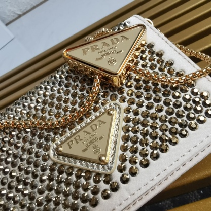 【 原單】🎉2023新款金色系項鍊水晶小包🎉1MR024🎉🎉這款Duchesse面料卡片夾通體飾以仿水晶，於表面營造出光影格調和虹彩炫色，彰顯華美且不失功能性的設計。最愛是這條可拆卸可調節鐵璉肩帶，又可當腰包裝飾😍😍又可當搭配衣服項鍊裝飾，中間三角形標可調節活動，賦予單品多樣的佩戴方式。空間可裝口紅💄/耳機/鑰匙🚗....夜燈下bling bling,太美了。值得入手🎉🎉尺寸：長11.5cm*高8cm