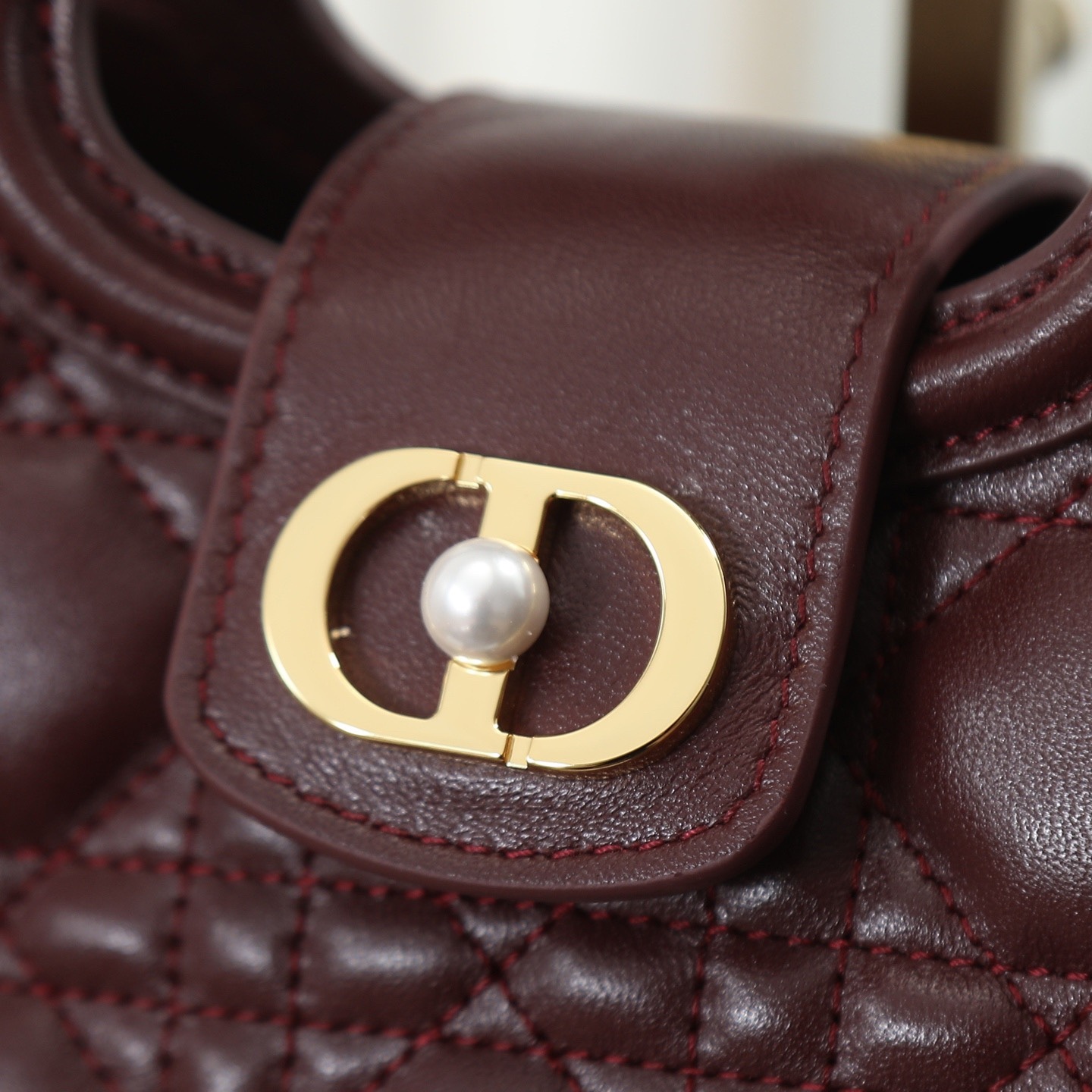 原廠級 酒紅色鏈條手袋
這款 Dior Jolie Top Handle 迷你鏈條手袋是二零二六早春成衣系列新品，呈現出優雅精緻的設計。採用黑色羊皮革精心製作，飾以藤格紋，翻蓋點綴以金色飾面金屬 CD 標誌和白色樹脂珠飾。內設一個隔層，可收納各種日常用品。搭配雙頂部手柄和可調節、可拆卸 CD 鏈條肩帶，肩帶由皮革帶和 CD 鏈環組成，飾以白色樹脂珠飾，可舒適手提、肩背或斜挎，可與日常或晚裝造型搭配。
