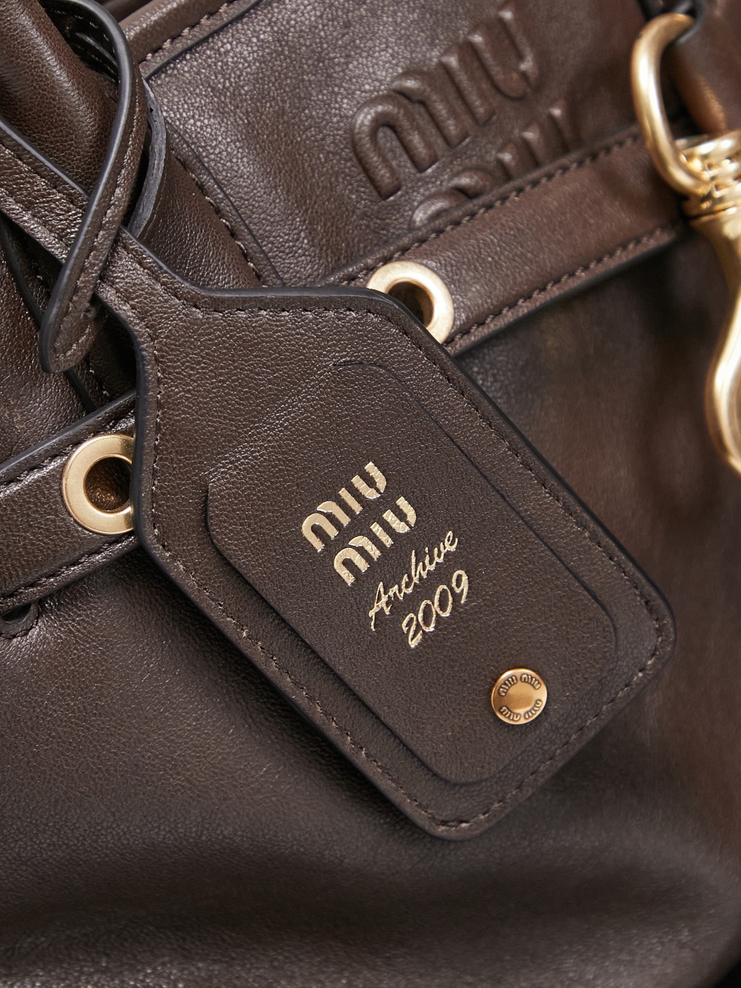 Aventure包袋展现出简约随性的魅力。重新诠释经典线条，这款柔软的Nappa变体展现出多功能和实用的态度，并通过精致独特的细节得到提升。aventure nappa皮革手袋灵感源自miu典藏设计，结构经过调整，变得更加轻便，焕发全新个性，饰以压花字母徽标，增添标志性元素，复古金色五金配件，亚麻混纺衬里，配拉链口袋和贴袋，长手腕适合用作手提或单肩