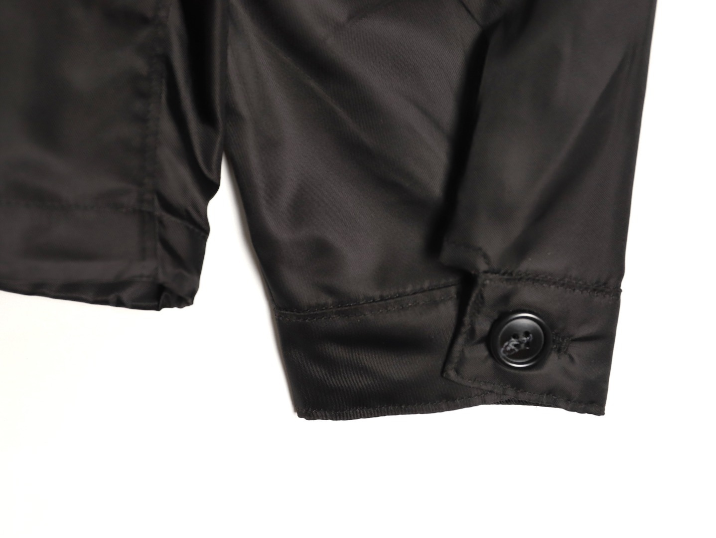 🔝PRADA/普拉達PRD 拉鍊口袋尼龍連帽外套
選用品牌標誌性的再生尼龍面料，與傳統尼龍性能相當，具備高強度，抗撕裂，耐磨損等特性。其質地輕盈，同時又具備防水功能適合多場景需求。抗皺，快乾的特點也易於日常打理維護。
定制三角徽標通過4個0.8mm金屬爪釘固定於衣身，爪釘背面經手工打磨至圓潤，避免刮蹭。下擺彈力抽繩選用7芯高彈尼龍繩，直徑3mm，配合橡膠扣，可實現±5cm長度調節。抽繩孔採用「金屬雞眼+防磨環」雙重保護，雞眼內徑5mm，邊緣光滑無毛刺，反復抽拉500次無變形。
袖口採用紐扣調