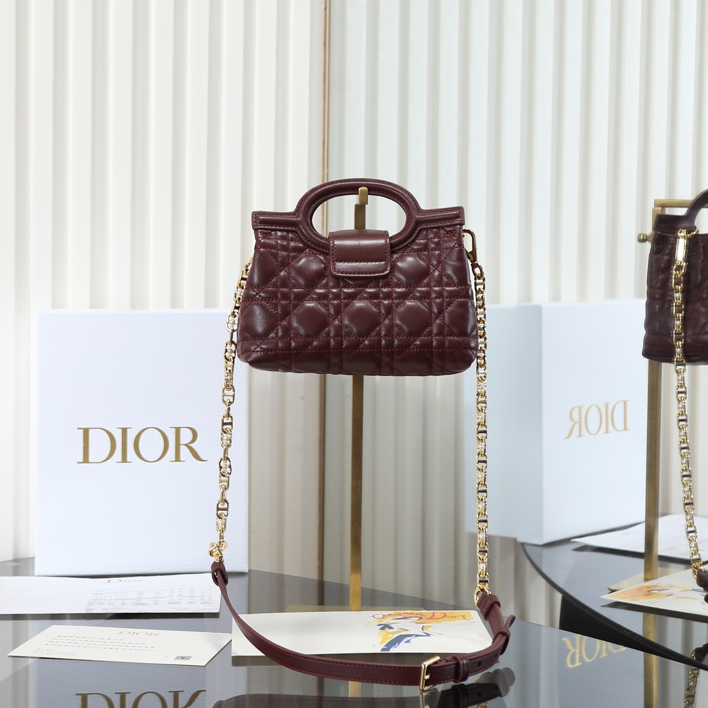 原廠級 酒紅色鏈條手袋
這款 Dior Jolie Top Handle 迷你鏈條手袋是二零二六早春成衣系列新品，呈現出優雅精緻的設計。採用黑色羊皮革精心製作，飾以藤格紋，翻蓋點綴以金色飾面金屬 CD 標誌和白色樹脂珠飾。內設一個隔層，可收納各種日常用品。搭配雙頂部手柄和可調節、可拆卸 CD 鏈條肩帶，肩帶由皮革帶和 CD 鏈環組成，飾以白色樹脂珠飾，可舒適手提、肩背或斜挎，可與日常或晚裝造型搭配。
