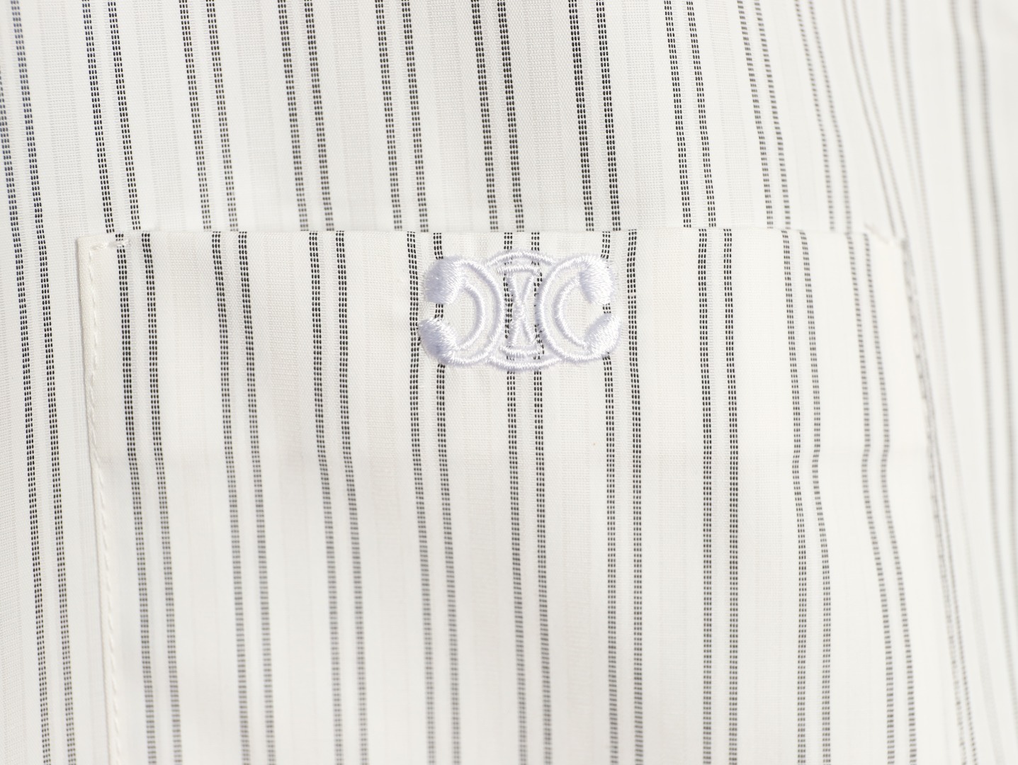 🔝CELINE賽琳CE 凱旋門竪條紋刺繡長袖襯衫
採用100%天然棉花纖維，無任何化纖混紡，從源頭確保面料的純淨度。棉纖維內部的中空結構形成天然“空氣通道”，使面料具備優異的透氣性。空氣可自由流通於纖維間隙，快速排出體表濕氣與熱量，即使長時間穿著也能保持乾爽，避免悶熱黏膩感。同時吸濕性遠超合成纖維。當人體出汗時，面料能迅速吸收汗液並擴散至表面，通過空氣流動加速蒸發，實現“吸濕-釋放”的動態平衡，保持肌膚乾爽舒適。
繡花機以棉線勾勒標誌，針腳細密均勻，確保線條流暢清晰，形成飽滿的立體肌理。刺繡