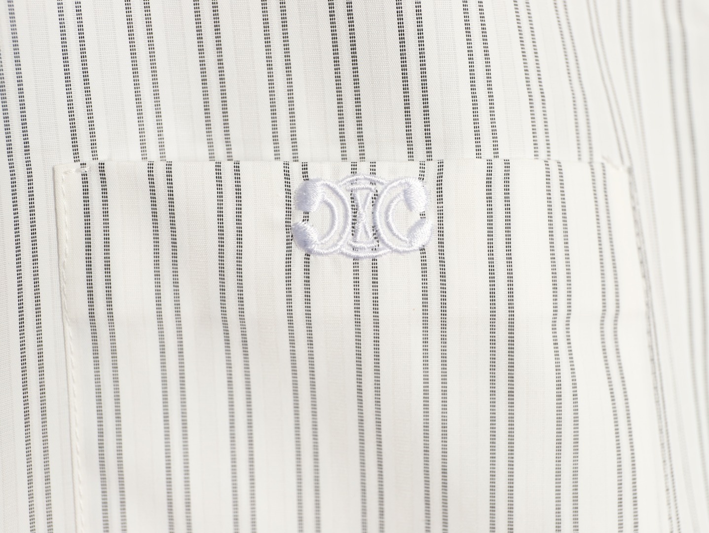 🔝CELINE賽琳CE 凱旋門竪條紋刺繡長袖襯衫
採用100%天然棉花纖維，無任何化纖混紡，從源頭確保面料的純淨度。棉纖維內部的中空結構形成天然“空氣通道”，使面料具備優異的透氣性。空氣可自由流通於纖維間隙，快速排出體表濕氣與熱量，即使長時間穿著也能保持乾爽，避免悶熱黏膩感。同時吸濕性遠超合成纖維。當人體出汗時，面料能迅速吸收汗液並擴散至表面，通過空氣流動加速蒸發，實現“吸濕-釋放”的動態平衡，保持肌膚乾爽舒適。
繡花機以棉線勾勒標誌，針腳細密均勻，確保線條流暢清晰，形成飽滿的立體肌理。刺繡