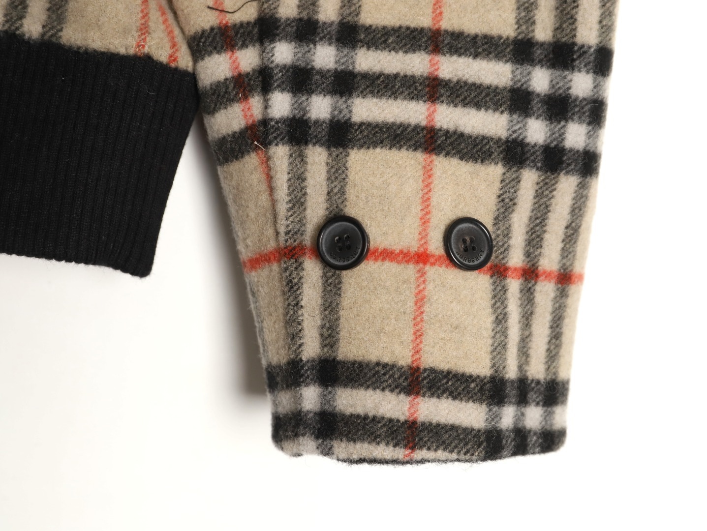 🔝BURBERRY巴寶莉BBR 雙面穿羊毛連帽外套
精選雙面羊毛斜紋面料，通過獨特的拉絨工藝處理，使表層呈現細膩豐盈的絨毛質感，觸感如雲朵般柔軟親膚，同時保留羊毛天然的保暖性與透氣性。一面以沈穩黑色演繹低調奢華，另一面則鋪滿標誌性的紅、黑、駝三色交織的經典圖案，既是品牌視覺符號，也為穿搭注入復古氣息。雙面可穿的設計，讓一件外套擁有兩種風格。
選用優質羊絨纖維進行精細紡紗，確保紗線的均勻性和強度。然後，通過先進的織造技術將紗線織成具有雙面效果的毛呢面料。
面料在裁剪前會經過預縮處理