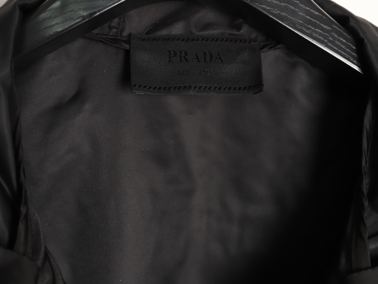🔝PRADA/普拉達PRD 拉鍊口袋尼龍連帽外套
選用品牌標誌性的再生尼龍面料，與傳統尼龍性能相當，具備高強度，抗撕裂，耐磨損等特性。其質地輕盈，同時又具備防水功能適合多場景需求。抗皺，快乾的特點也易於日常打理維護。
定制三角徽標通過4個0.8mm金屬爪釘固定於衣身，爪釘背面經手工打磨至圓潤，避免刮蹭。下擺彈力抽繩選用7芯高彈尼龍繩，直徑3mm，配合橡膠扣，可實現±5cm長度調節。抽繩孔採用「金屬雞眼+防磨環」雙重保護，雞眼內徑5mm，邊緣光滑無毛刺，反復抽拉500次無變形。
袖口採用紐扣調