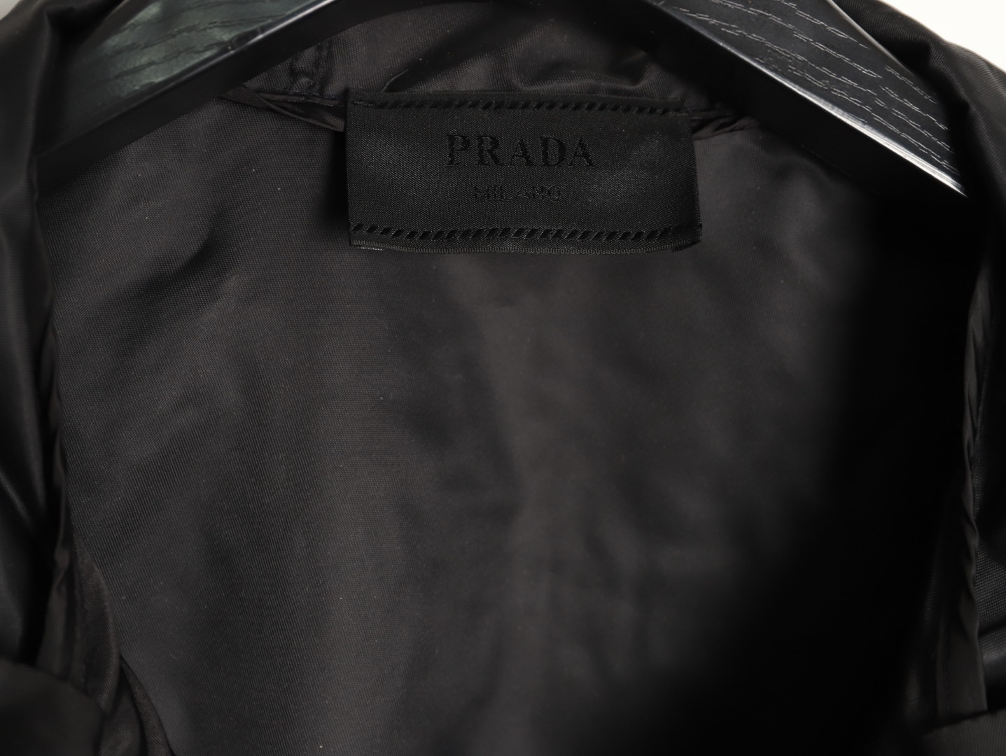 🔝PRADA/普拉達PRD 拉鍊口袋尼龍連帽外套
選用品牌標誌性的再生尼龍面料，與傳統尼龍性能相當，具備高強度，抗撕裂，耐磨損等特性。其質地輕盈，同時又具備防水功能適合多場景需求。抗皺，快乾的特點也易於日常打理維護。
定制三角徽標通過4個0.8mm金屬爪釘固定於衣身，爪釘背面經手工打磨至圓潤，避免刮蹭。下擺彈力抽繩選用7芯高彈尼龍繩，直徑3mm，配合橡膠扣，可實現±5cm長度調節。抽繩孔採用「金屬雞眼+防磨環」雙重保護，雞眼內徑5mm，邊緣光滑無毛刺，反復抽拉500次無變形。
袖口採用紐扣調
