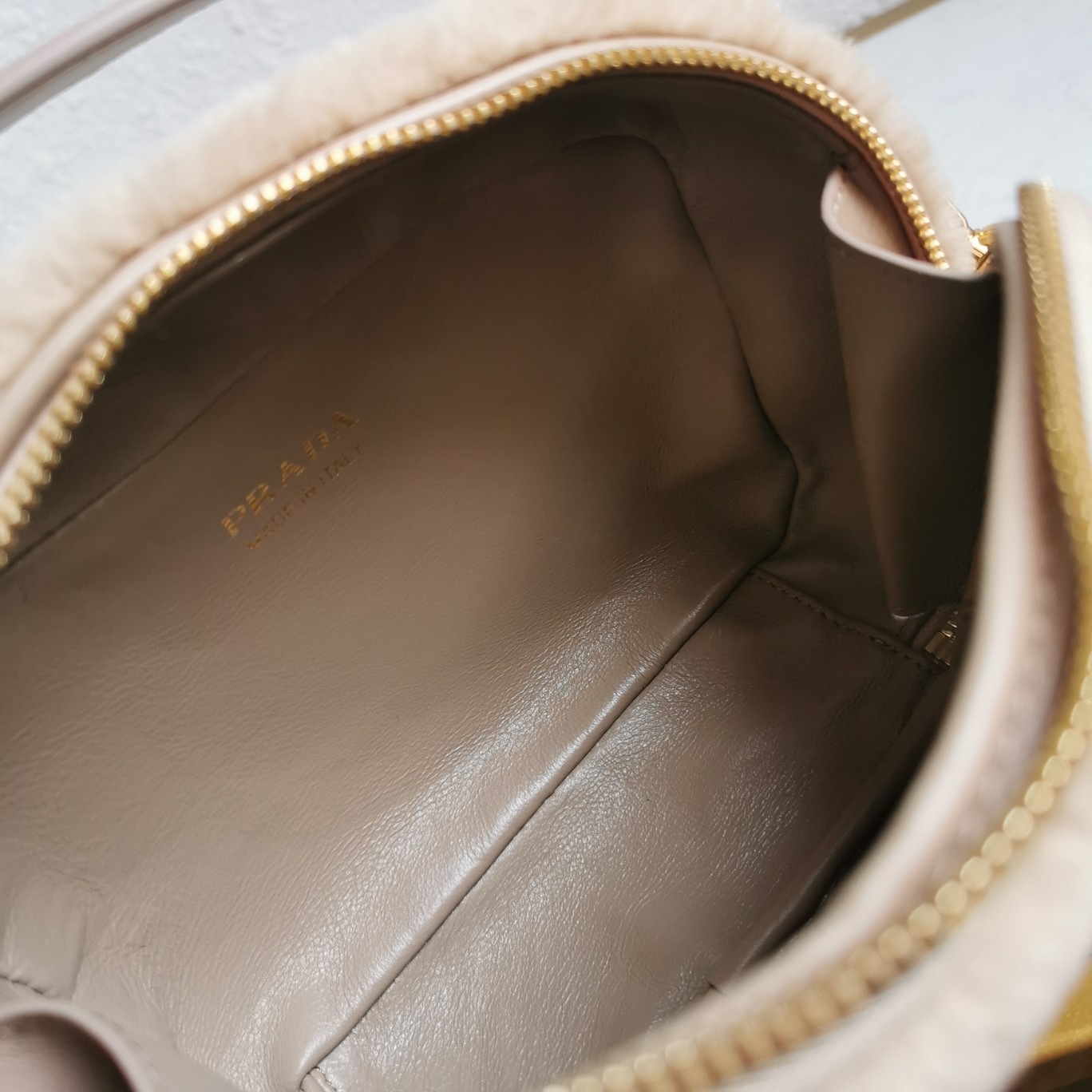 【 原單】🎉最新款迷你手袋🎉1BH208羊毛🎉🎉這款迷你手袋結構挺括，風格百搭，搭配柔軟的羊毛皮，彰顯冬日魅力。皮革細節與雙向拉鍊開合和金屬五金配件錦上添花，飾有塗琺瑯三角形金屬徽標。內配進口小羊皮，上身效果非常酷/時尚，冬天必備爆款🎉寶寶們，趕緊入手吧
尺寸：長19.5x高13x底6cm