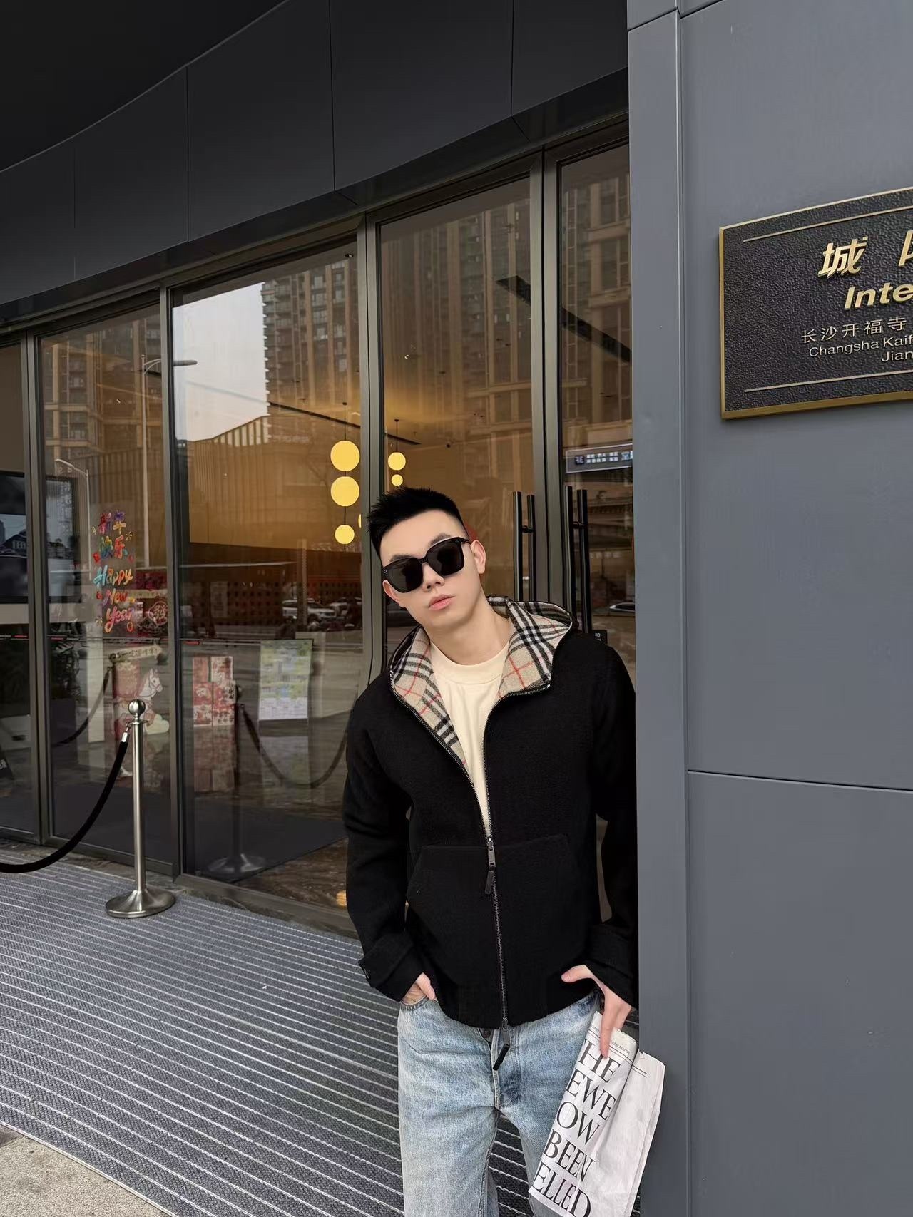 🔝BURBERRY巴寶莉BBR 雙面穿羊毛連帽外套
精選雙面羊毛斜紋面料，通過獨特的拉絨工藝處理，使表層呈現細膩豐盈的絨毛質感，觸感如雲朵般柔軟親膚，同時保留羊毛天然的保暖性與透氣性。一面以沈穩黑色演繹低調奢華，另一面則鋪滿標誌性的紅、黑、駝三色交織的經典圖案，既是品牌視覺符號，也為穿搭注入復古氣息。雙面可穿的設計，讓一件外套擁有兩種風格。
選用優質羊絨纖維進行精細紡紗，確保紗線的均勻性和強度。然後，通過先進的織造技術將紗線織成具有雙面效果的毛呢面料。
面料在裁剪前會經過預縮處理