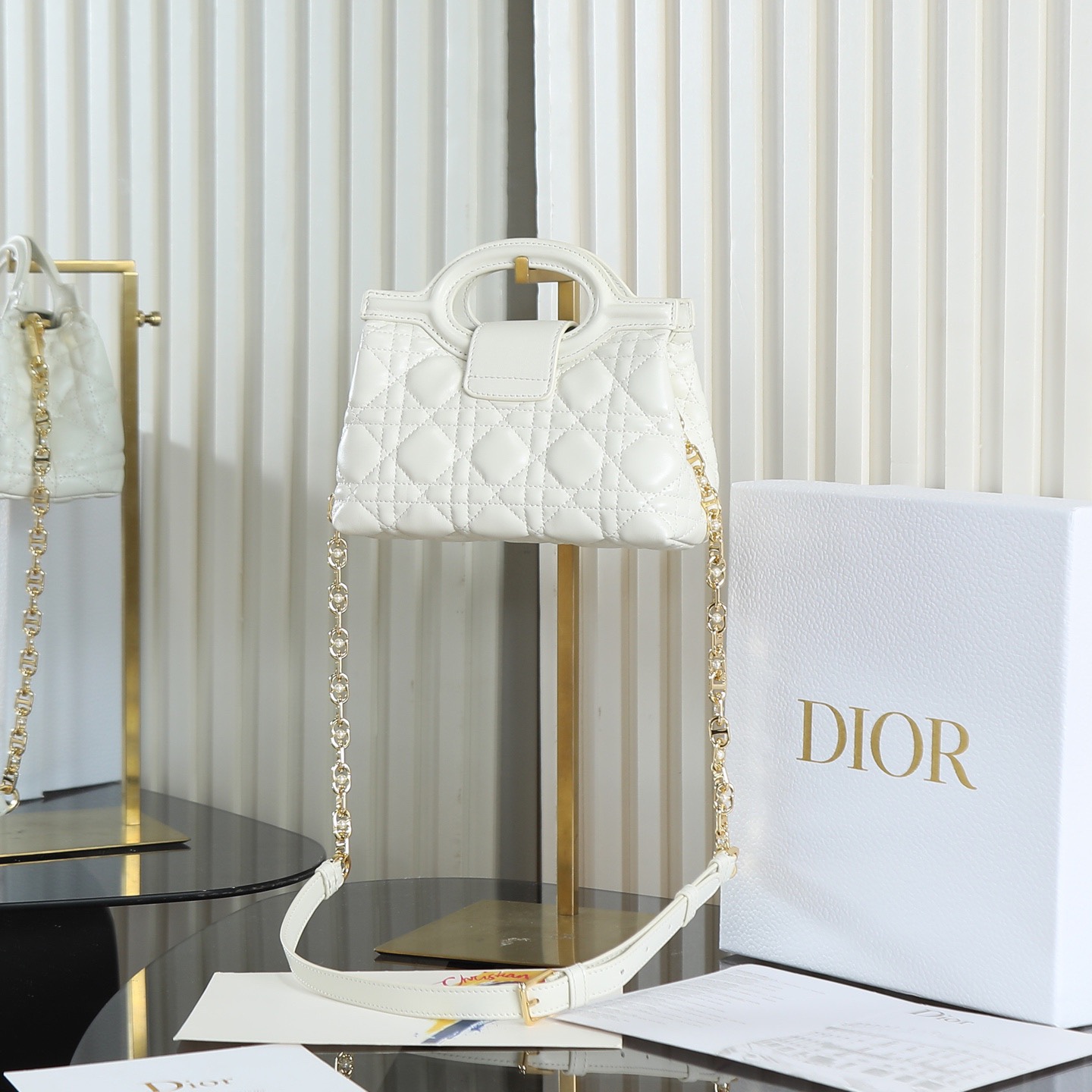 原廠級 白色鏈條手袋
這款 Dior Jolie Top Handle 迷你鏈條手袋是二零二六早春成衣系列新品，呈現出優雅精緻的設計。採用黑色羊皮革精心製作，飾以藤格紋，翻蓋點綴以金色飾面金屬 CD 標誌和白色樹脂珠飾。內設一個隔層，可收納各種日常用品。搭配雙頂部手柄和可調節、可拆卸 CD 鏈條肩帶，肩帶由皮革帶和 CD 鏈環組成，飾以白色樹脂珠飾，可舒適手提、肩背或斜挎，可與日常或晚裝造型搭配。
