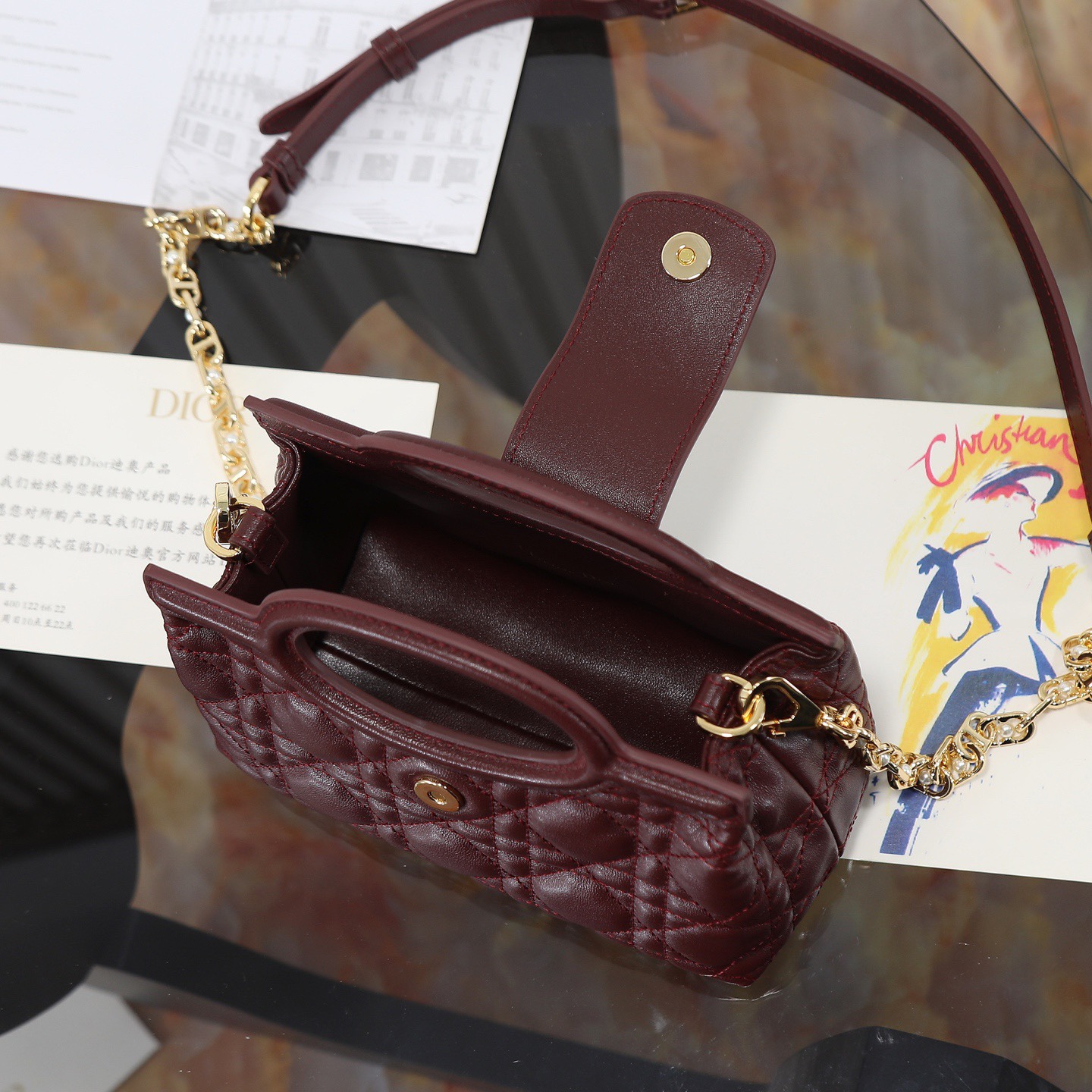 原廠級 酒紅色鏈條手袋
這款 Dior Jolie Top Handle 迷你鏈條手袋是二零二六早春成衣系列新品，呈現出優雅精緻的設計。採用黑色羊皮革精心製作，飾以藤格紋，翻蓋點綴以金色飾面金屬 CD 標誌和白色樹脂珠飾。內設一個隔層，可收納各種日常用品。搭配雙頂部手柄和可調節、可拆卸 CD 鏈條肩帶，肩帶由皮革帶和 CD 鏈環組成，飾以白色樹脂珠飾，可舒適手提、肩背或斜挎，可與日常或晚裝造型搭配。
