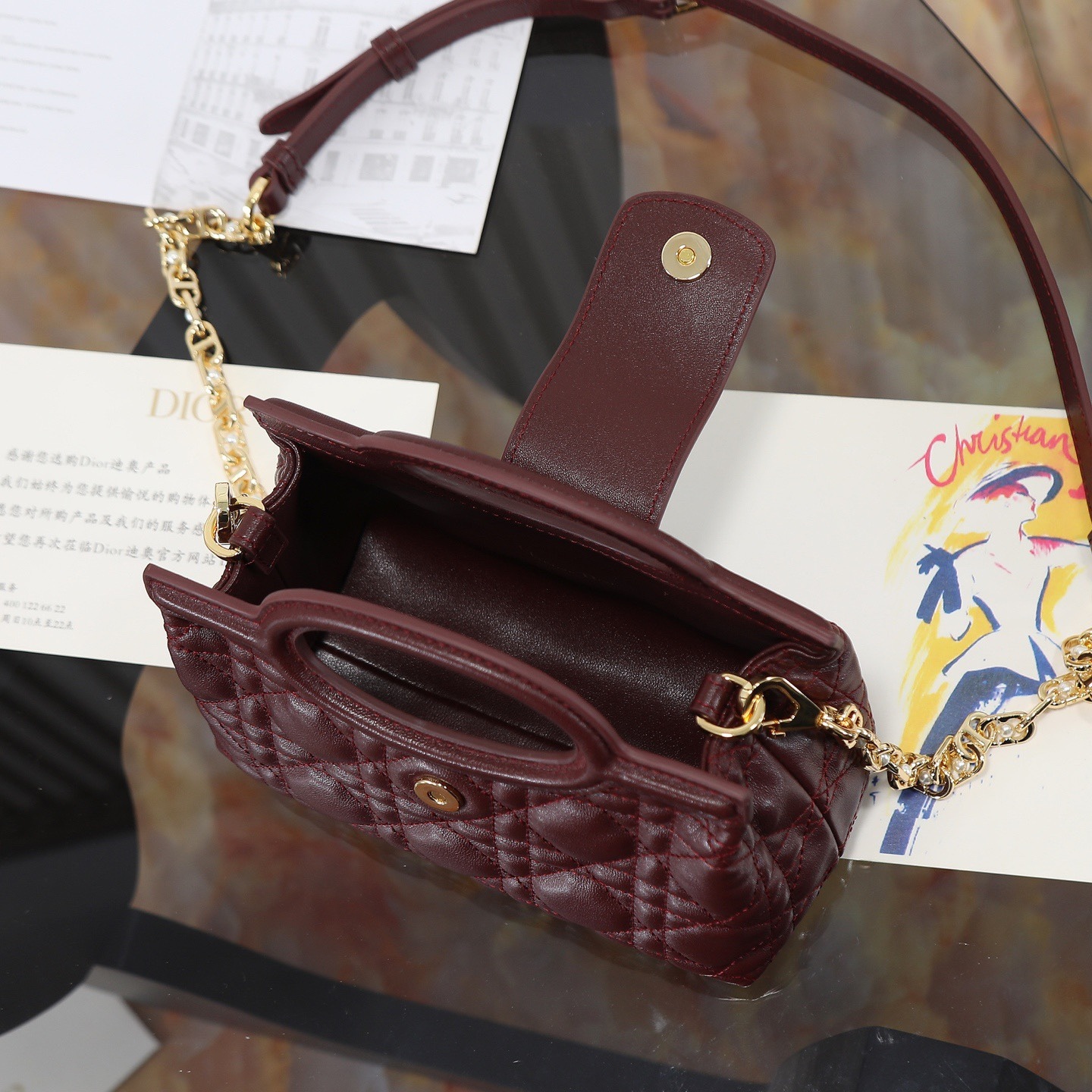 原廠級 酒紅色鏈條手袋
這款 Dior Jolie Top Handle 迷你鏈條手袋是二零二六早春成衣系列新品，呈現出優雅精緻的設計。採用黑色羊皮革精心製作，飾以藤格紋，翻蓋點綴以金色飾面金屬 CD 標誌和白色樹脂珠飾。內設一個隔層，可收納各種日常用品。搭配雙頂部手柄和可調節、可拆卸 CD 鏈條肩帶，肩帶由皮革帶和 CD 鏈環組成，飾以白色樹脂珠飾，可舒適手提、肩背或斜挎，可與日常或晚裝造型搭配。
