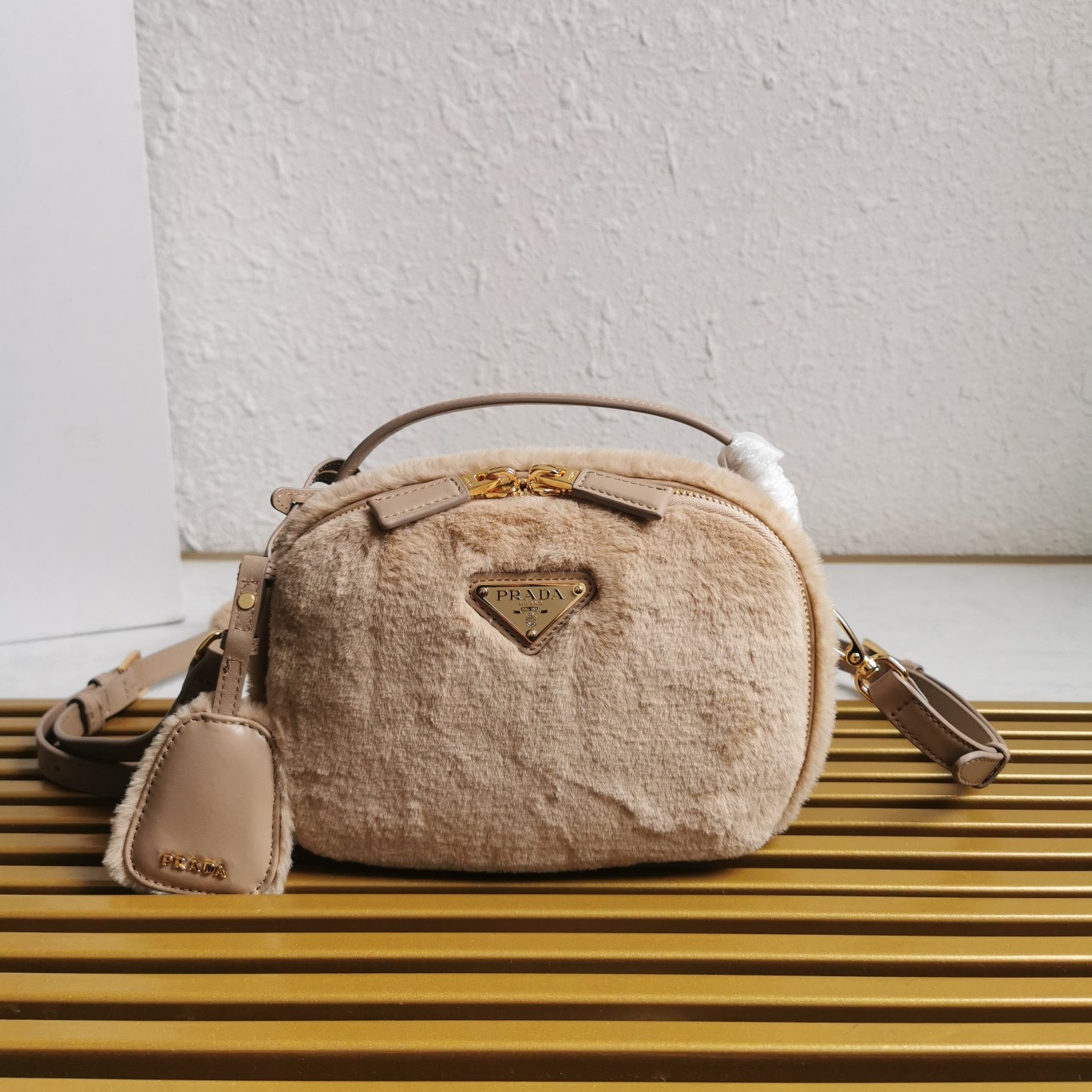 【 原單】🎉最新款迷你手袋🎉1BH208羊毛🎉🎉這款迷你手袋結構挺括，風格百搭，搭配柔軟的羊毛皮，彰顯冬日魅力。皮革細節與雙向拉鍊開合和金屬五金配件錦上添花，飾有塗琺瑯三角形金屬徽標。內配進口小羊皮，上身效果非常酷/時尚，冬天必備爆款🎉寶寶們，趕緊入手吧
尺寸：長19.5x高13x底6cm