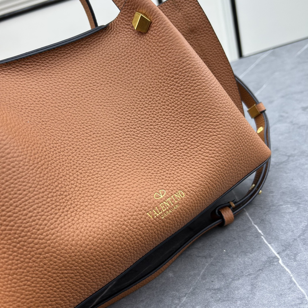 荔枝紋 Garavani VLOGO Escape 小牛皮小號購物袋，包袋兩側點綴紅色細節，金屬徽標飾件可用在包裝內部作為開合，亦可用在外部作為裝飾元素。
小號尺寸：31 *25*15 cm