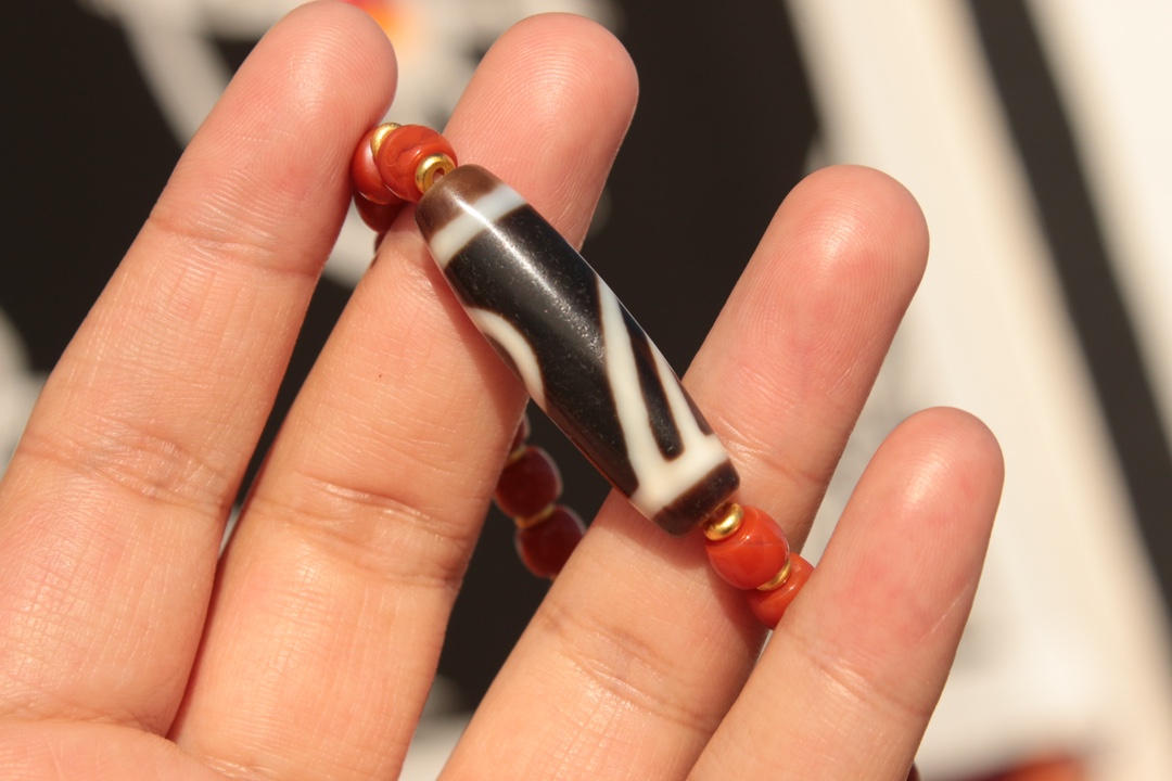 Tibetan sacred object - one-eyed dzi bead and red agate bracelet