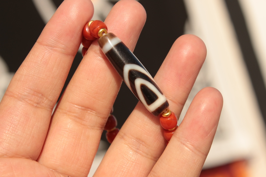 Tibetan sacred object - one-eyed dzi bead and red agate bracelet