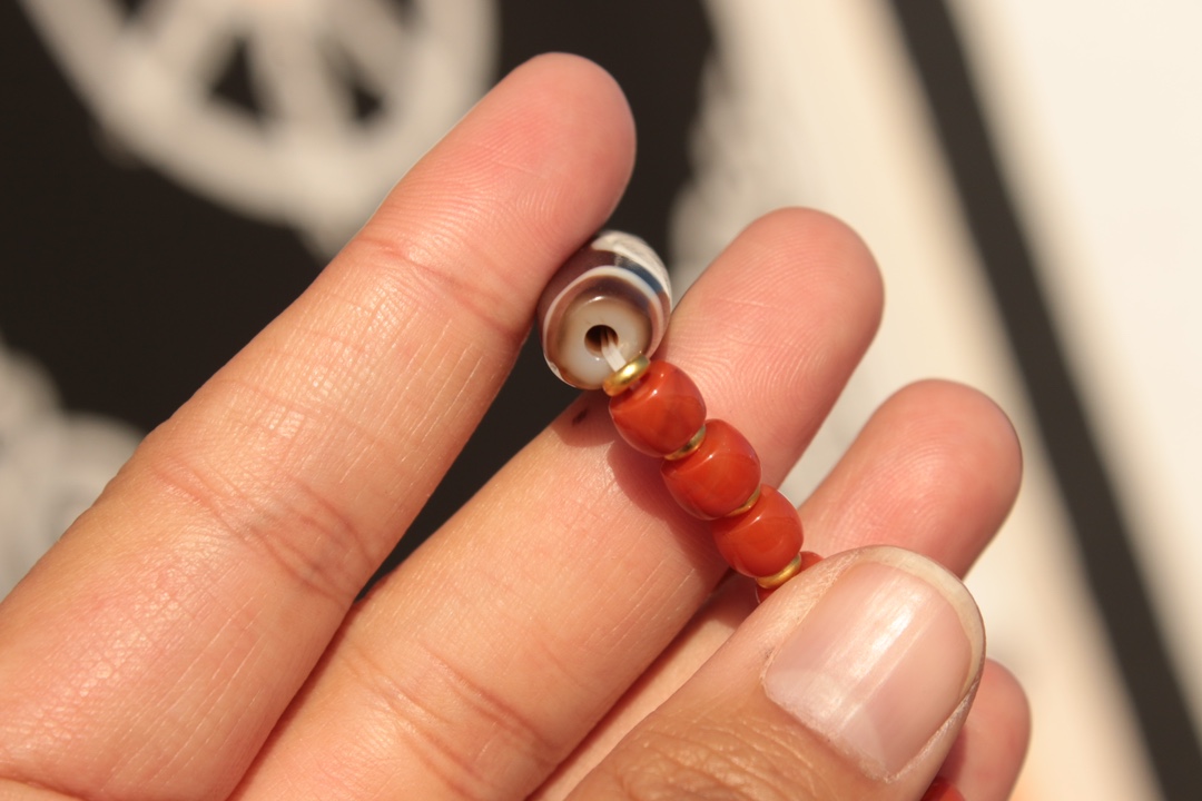Tibetan sacred object - one-eyed dzi bead and red agate bracelet