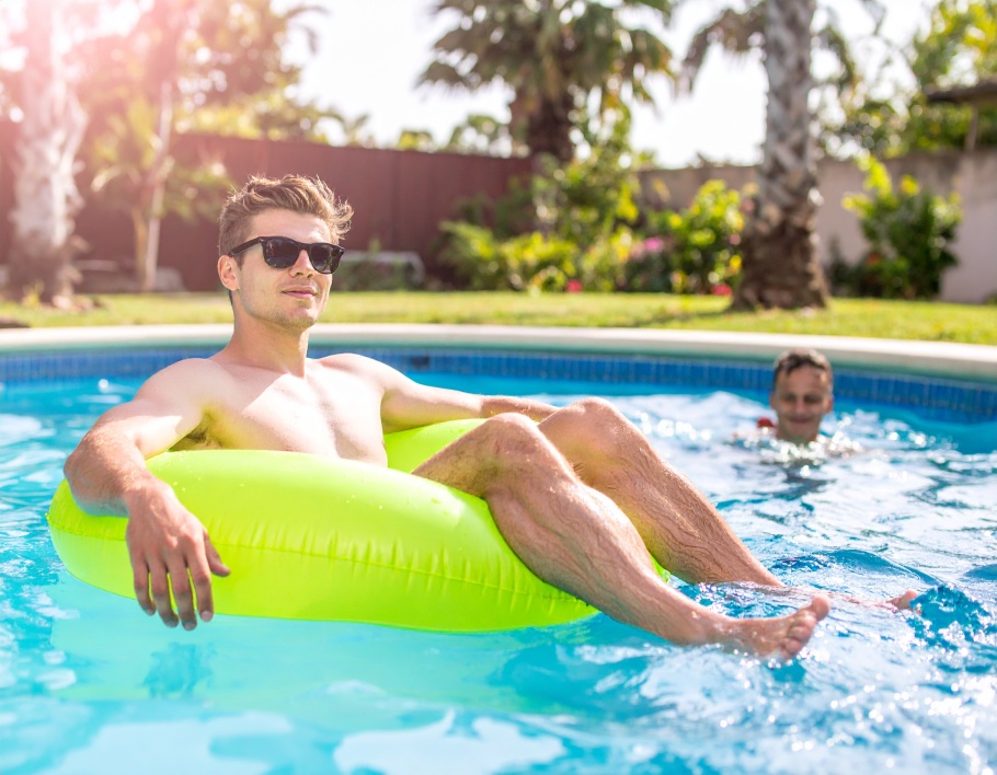 Firefly-Two-young-adults-floating-on-a-bright-lime-circular-inflatable-seat-in-a-backyard-poo-641560